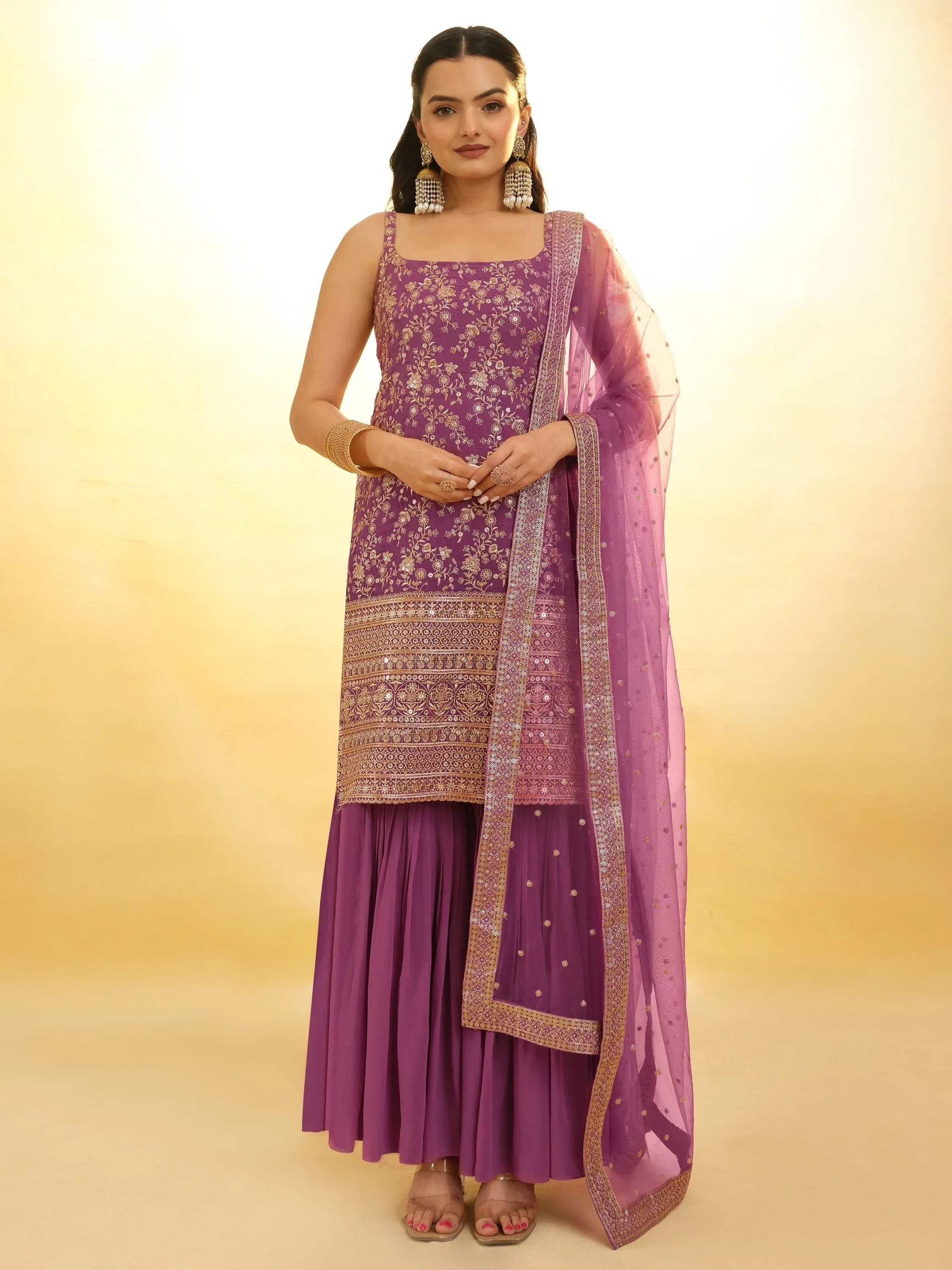 Woman wearing purple embroidered ethnic sharara suit with dupatta and jewelry