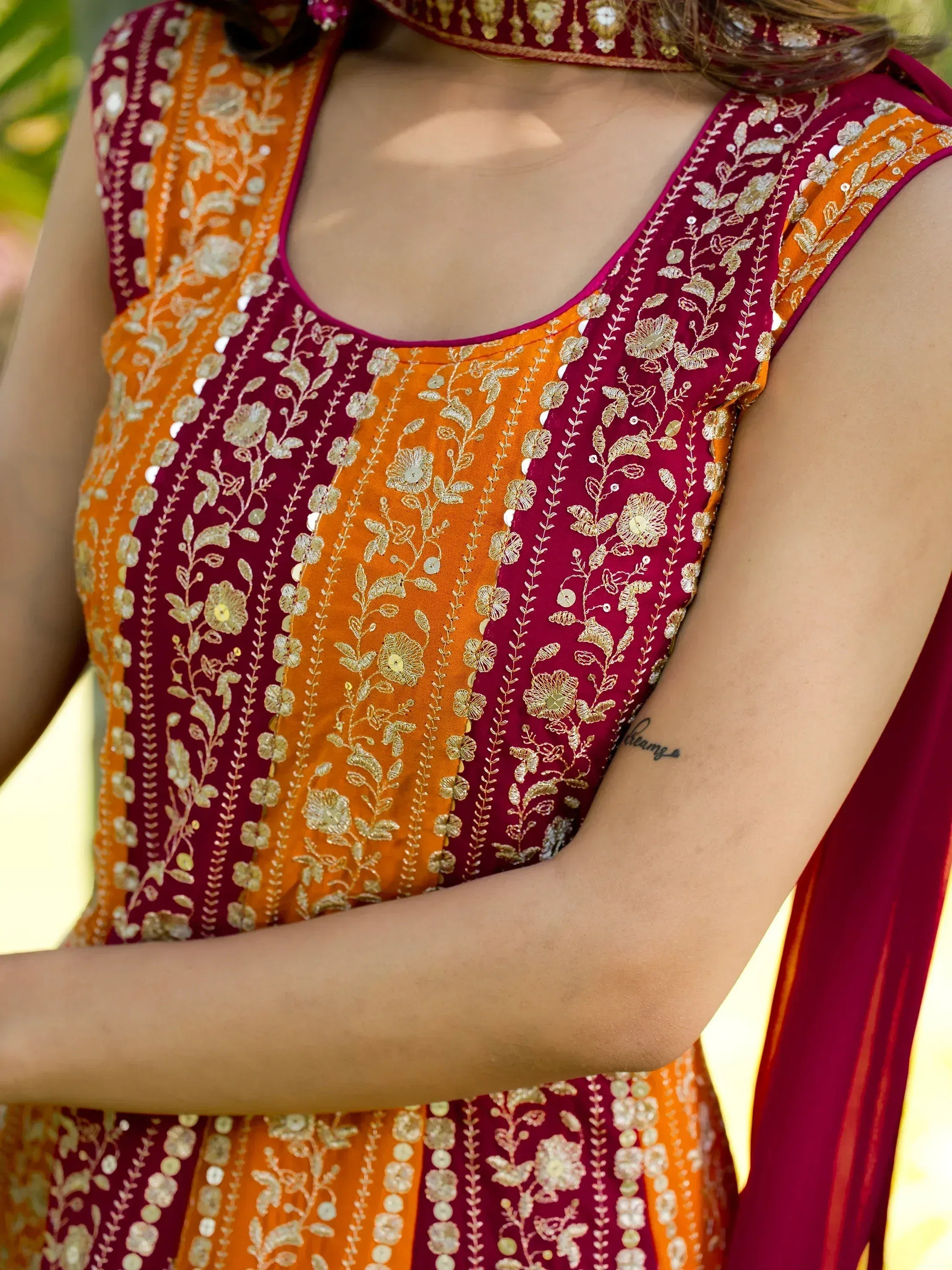 Maroon and orange ethnic gown with gold floral embroidery and mirror work, perfect for Indian occasions