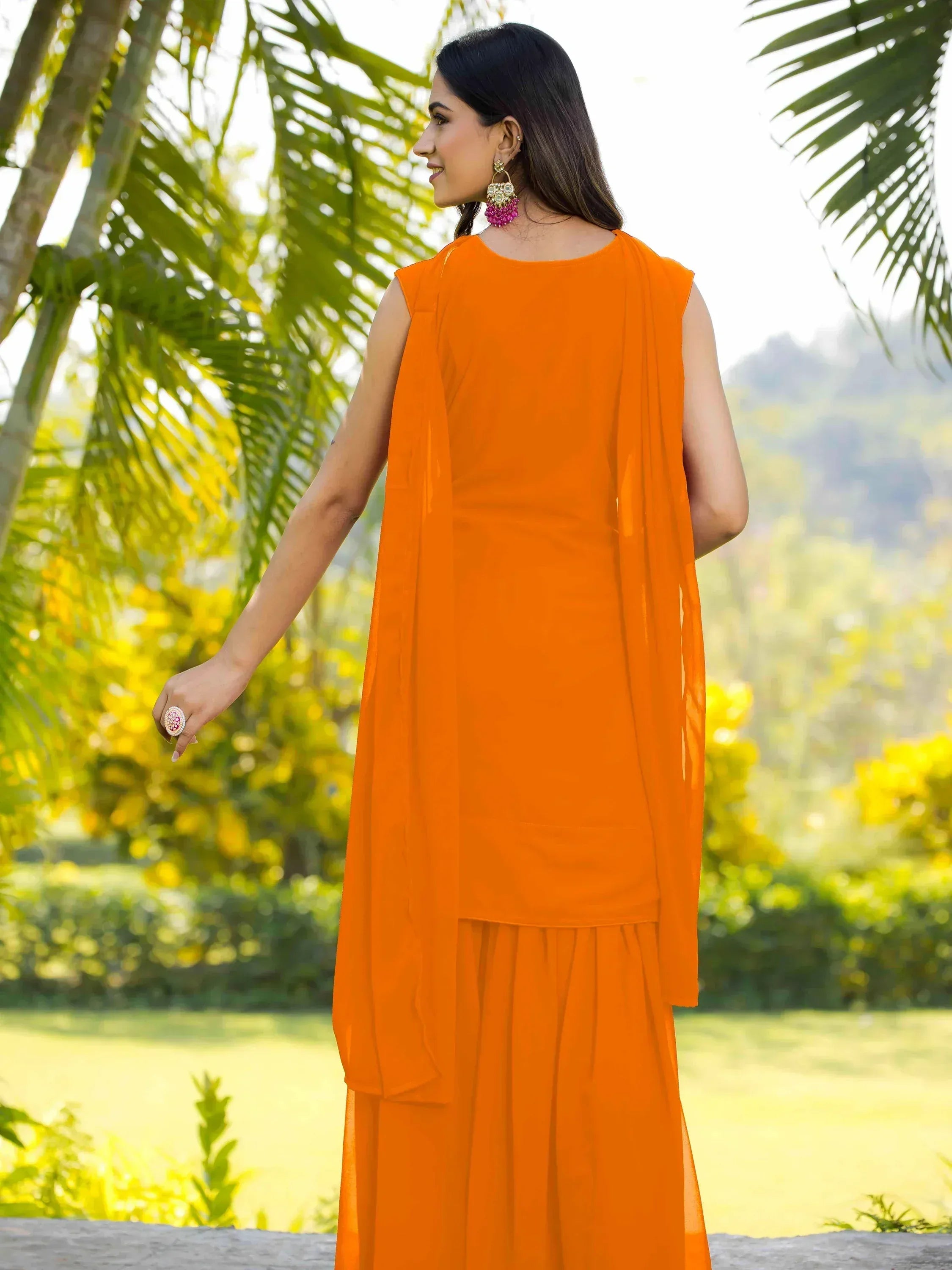 Vibrant orange ethnic gown with matching dupatta, styled with statement earrings for festive occasions