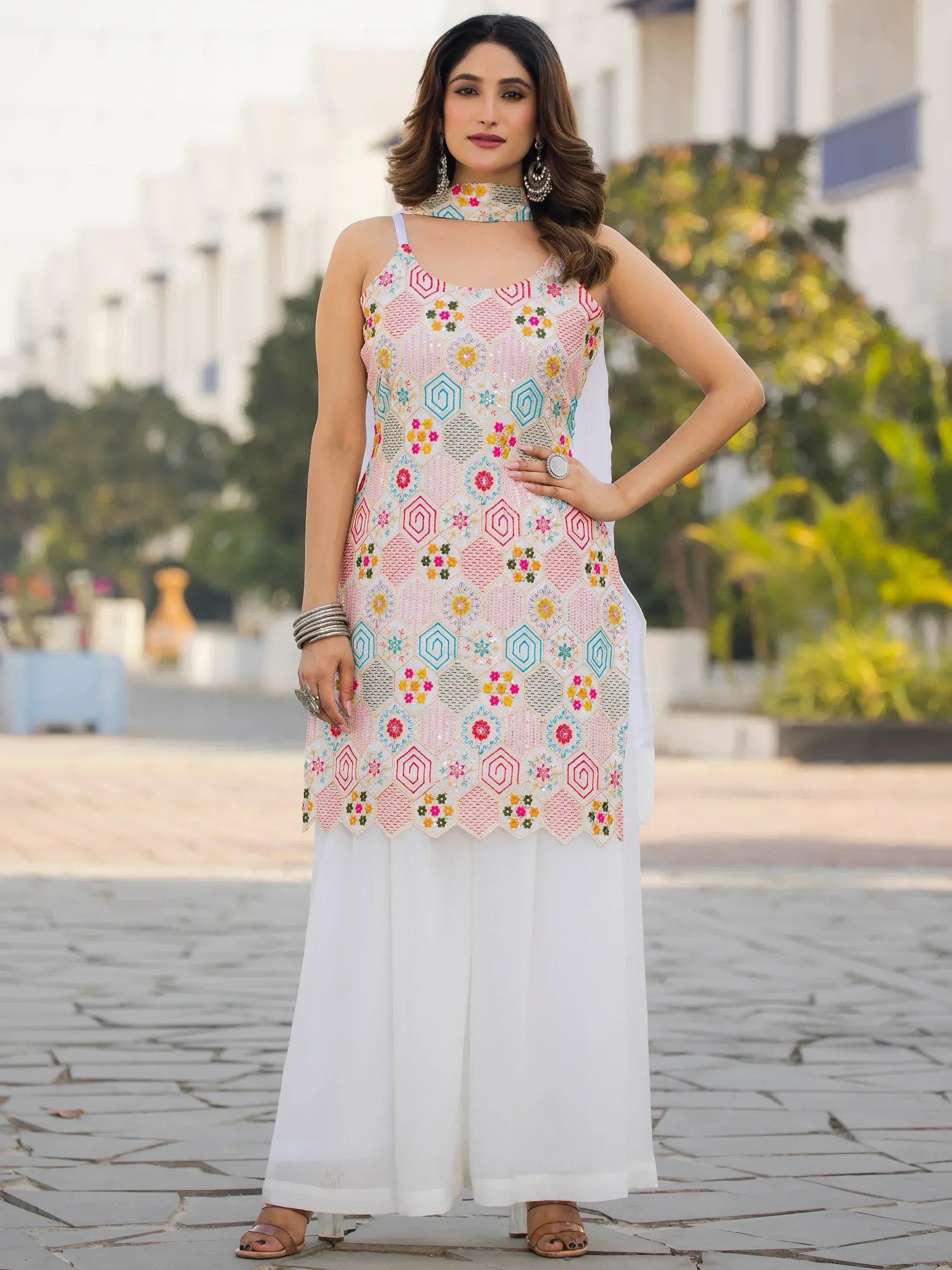Woman in embroidered white ethnic kurta with colorful geometric patterns and palazzo pants, perfect for Indian occasions.