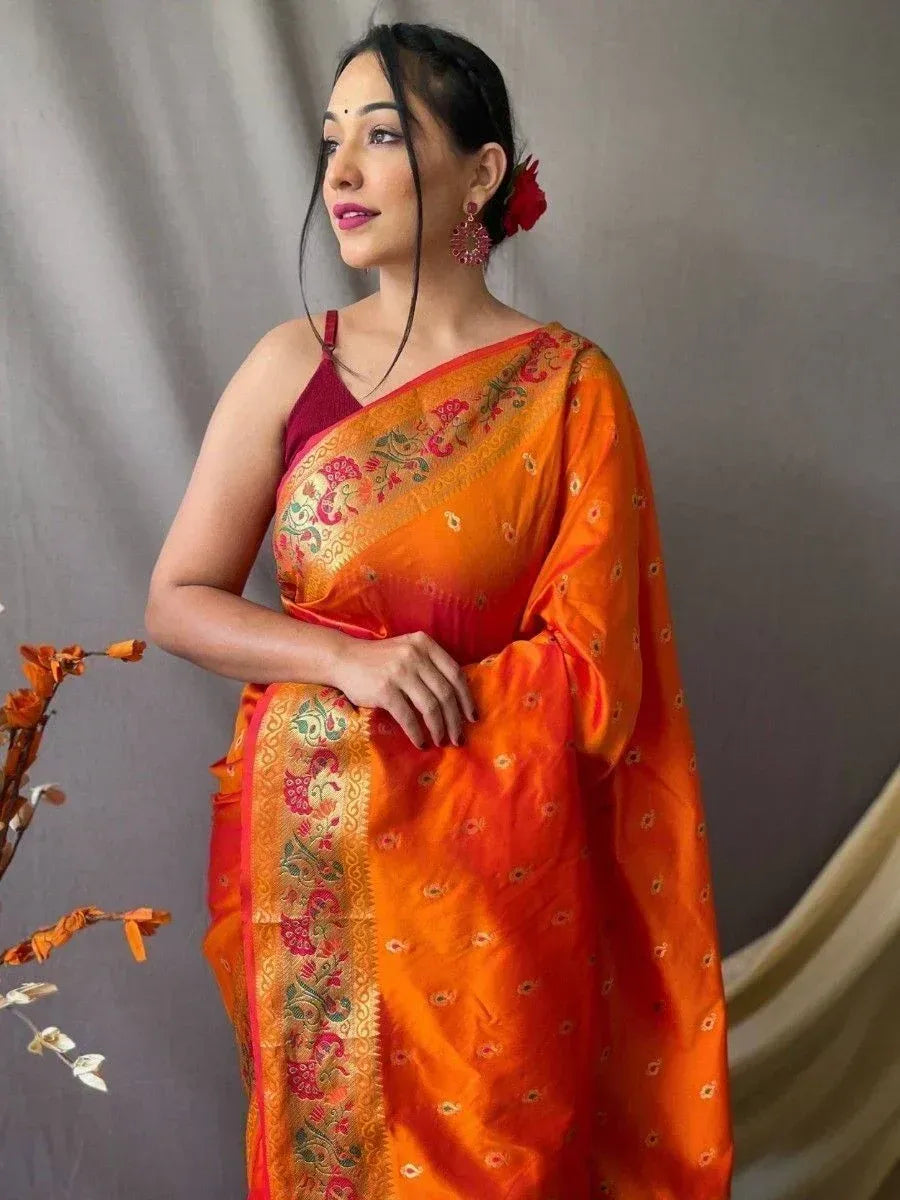Vibrant orange designer saree with floral embroidery and gold border, paired with maroon blouse for ethnic wear
