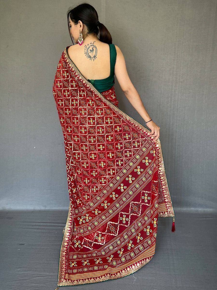 Red embroidered saree with gold patterns, paired with green blouse, showcasing ethnic Indian wear