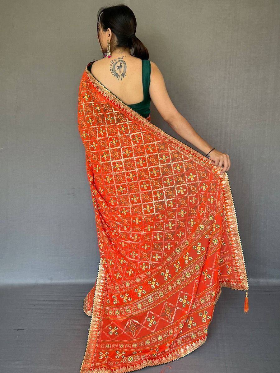 Woman in vibrant orange ethnic saree with gold embroidery and tassels, paired with green blouse