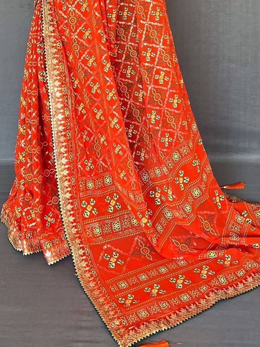 Vibrant orange ethnic saree with intricate geometric prints and golden border detailing