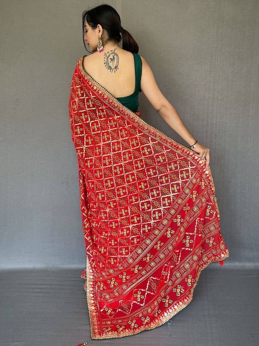 Red embroidered saree with gold patterns, paired with green blouse, showcasing ethnic Indian wear