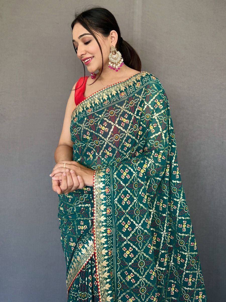 Woman in green printed saree with gold border, red blouse, and ethnic jewelry for Indian occasions