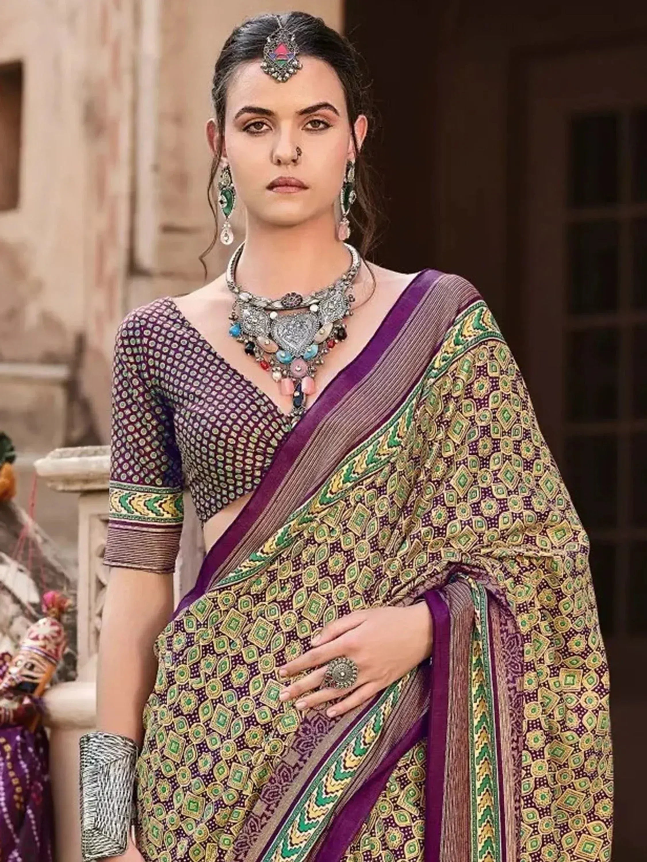 Woman in purple and green printed saree with ethnic jewelry, traditional Indian attire