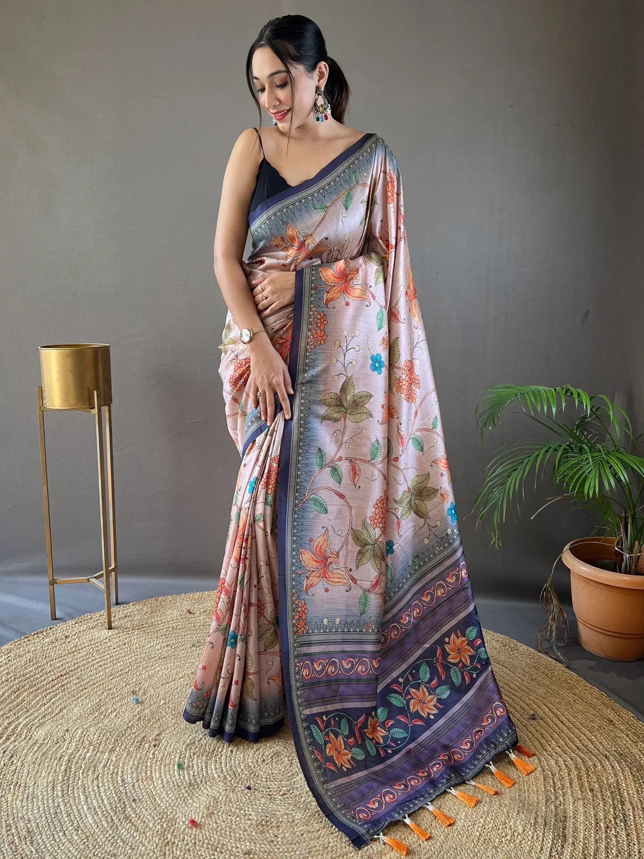 Woman wearing floral printed saree with navy border and tassels, styled with black blouse for ethnic occasions