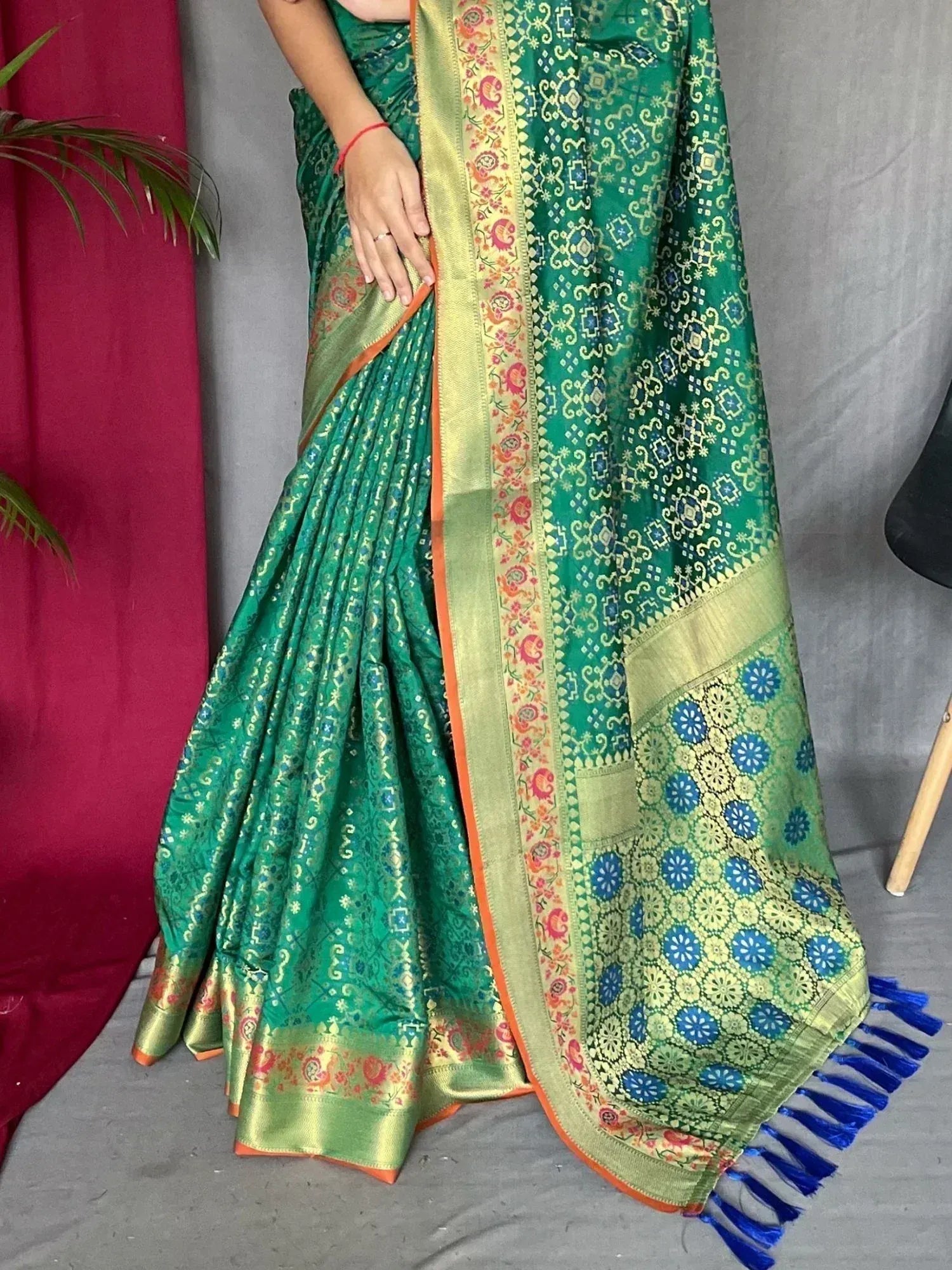 Emerald green designer saree with gold paisley border and blue floral pallu, perfect for Indian ethnic wear