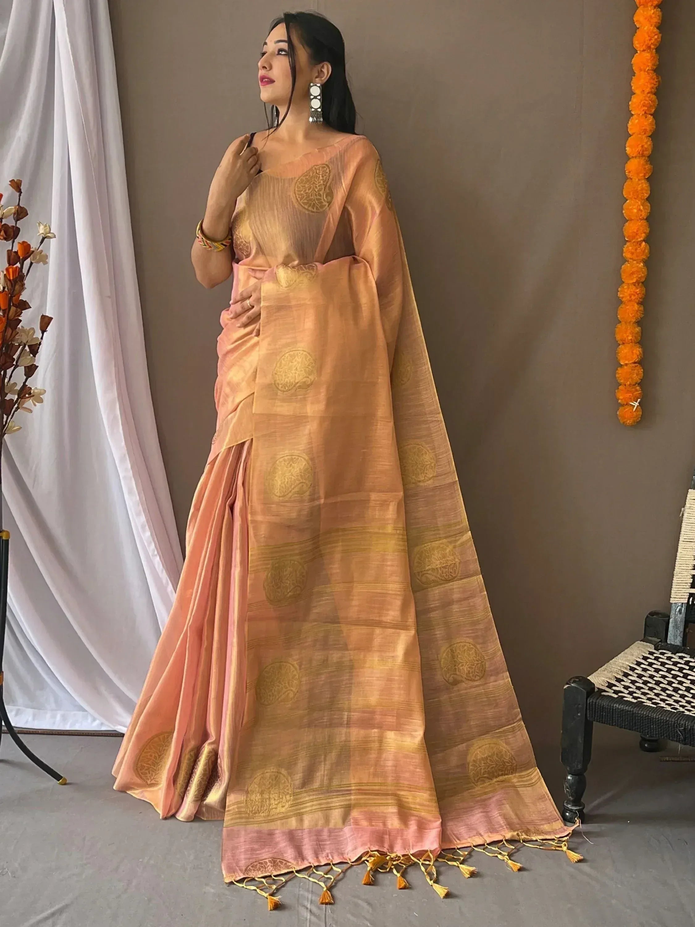 Peach and gold designer saree with floral motifs and tassels, perfect for Indian ethnic wear occasions