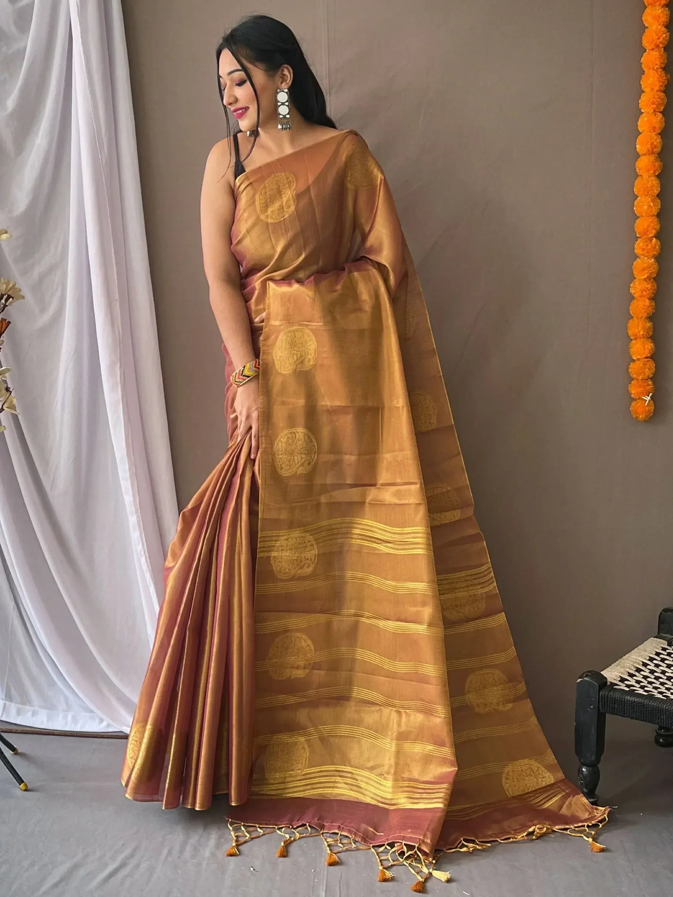 Woman in elegant golden brown silk saree with circular motifs and tassels, perfect for Indian ethnic occasions.