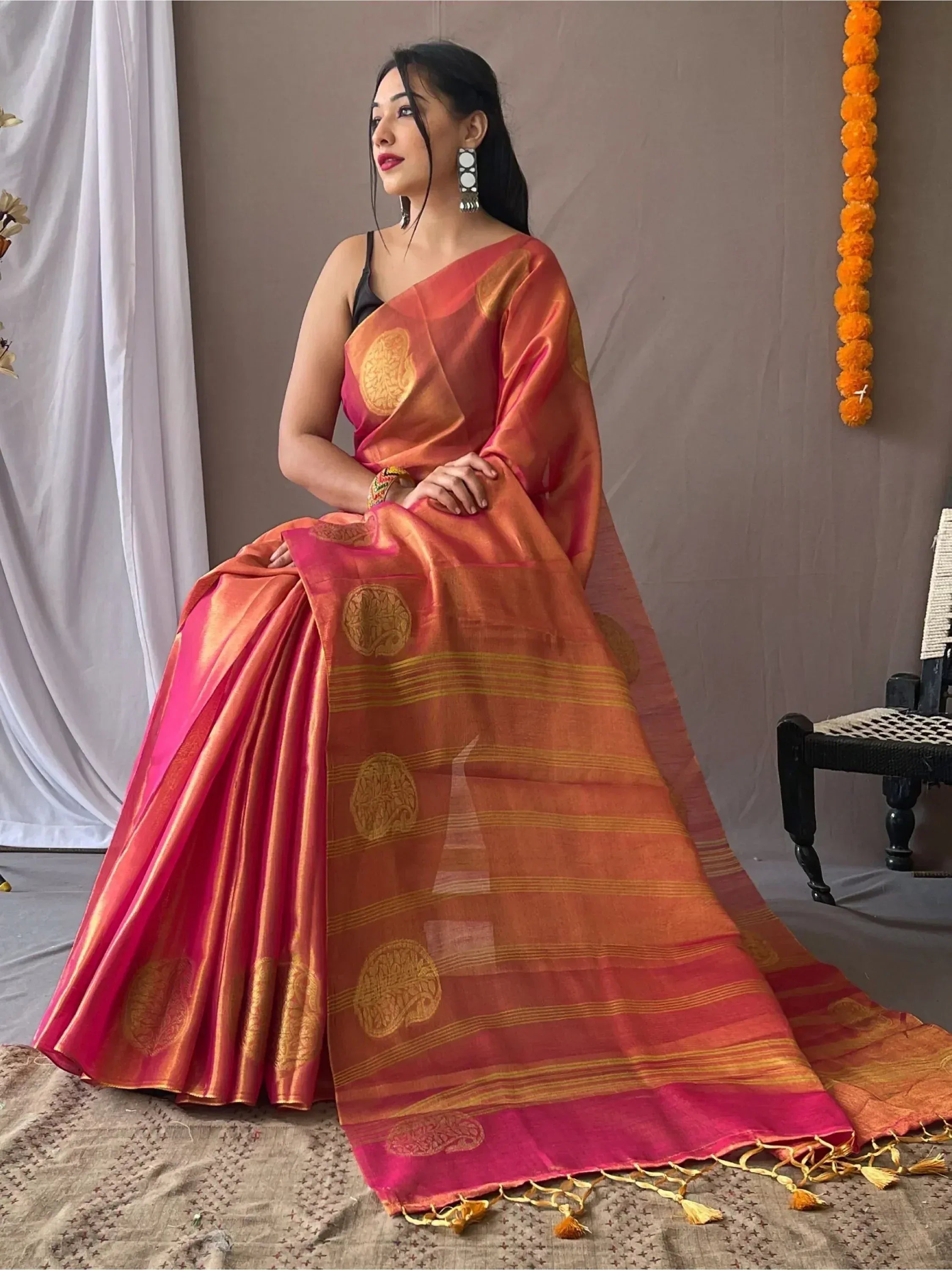 Woman in vibrant orange and pink ethnic saree with gold motifs, perfect for Indian occasions
