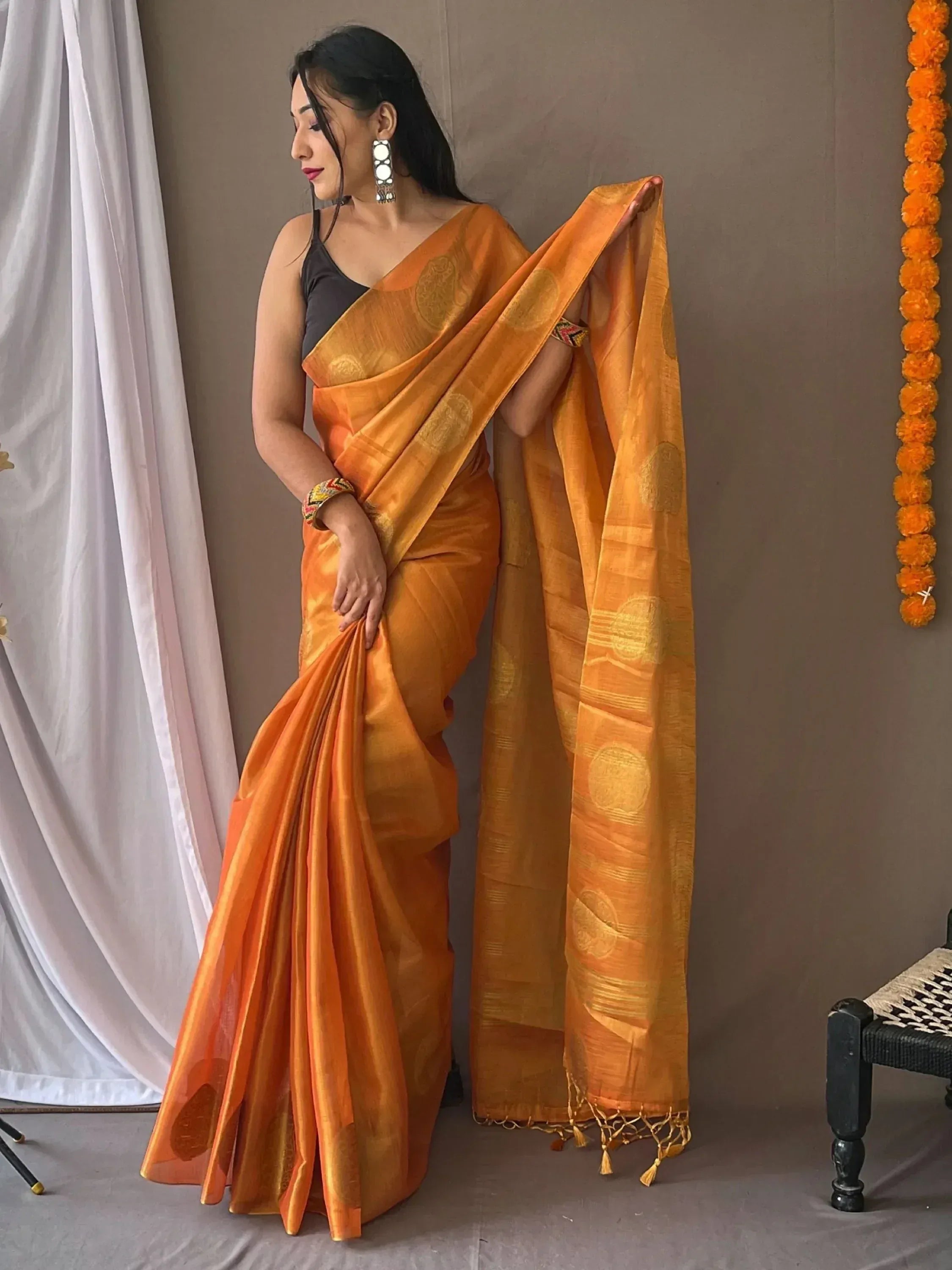 Woman in vibrant orange ethnic saree with gold motifs, perfect for Indian occasions and festive wear.