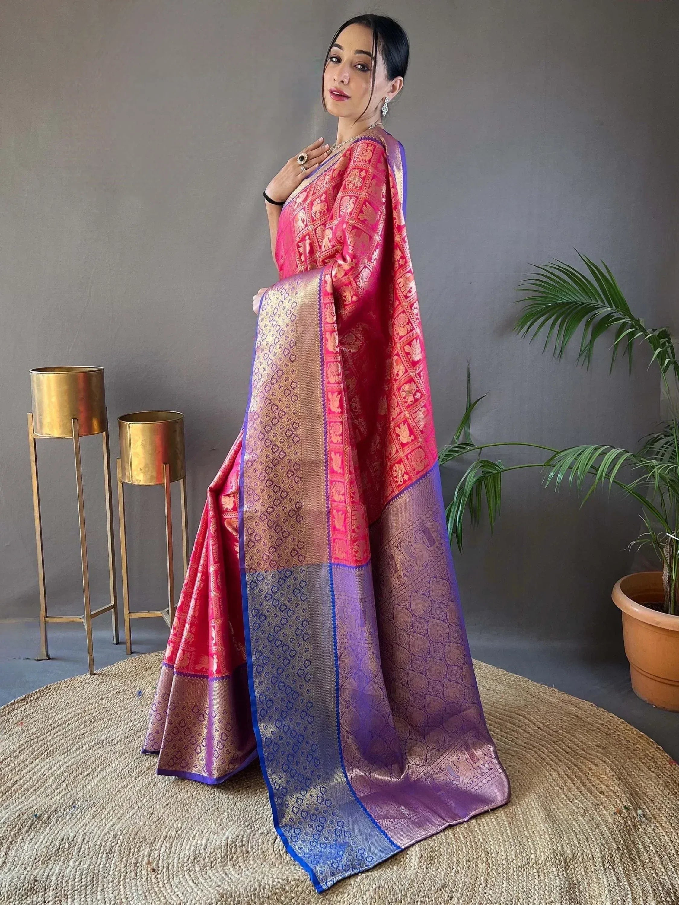 Woman in vibrant pink and purple designer saree with intricate elephant motifs and gold border, perfect for Indian ethnic wear occasions.
