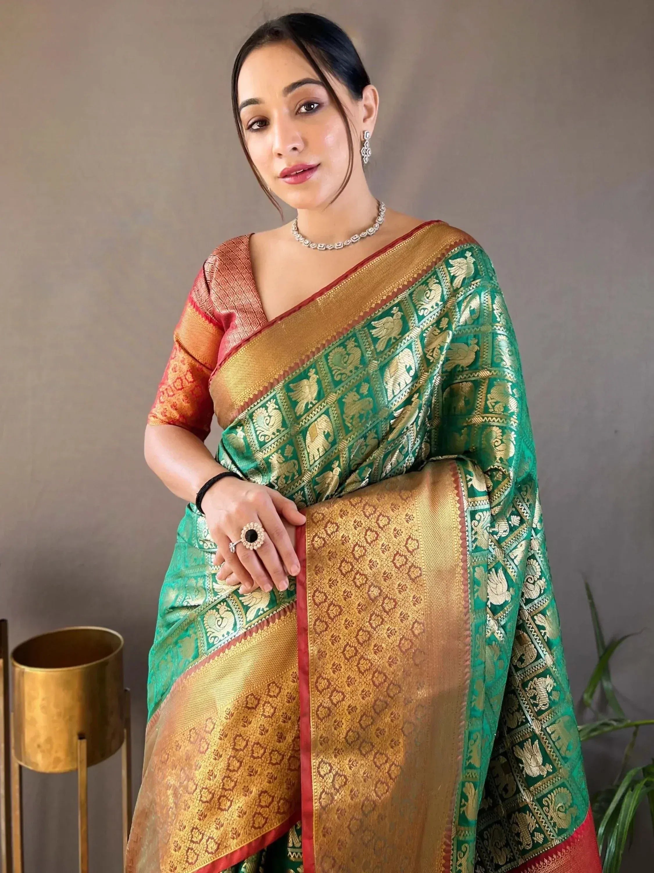 Woman in green and gold designer saree with elephant motifs, perfect for Indian ethnic wear occasions.