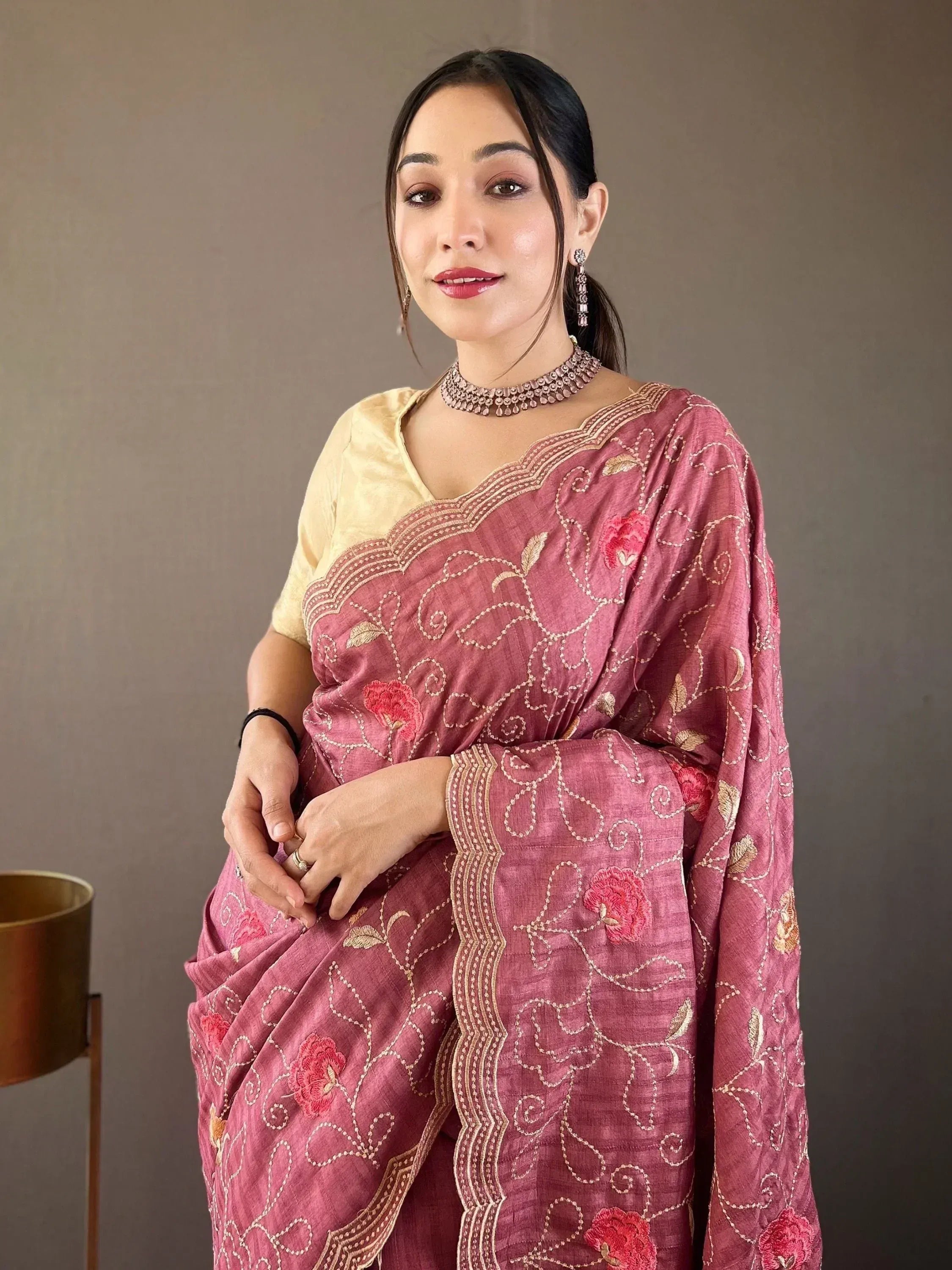 Pink embroidered saree with gold floral motifs and yellow blouse, styled with traditional jewelry