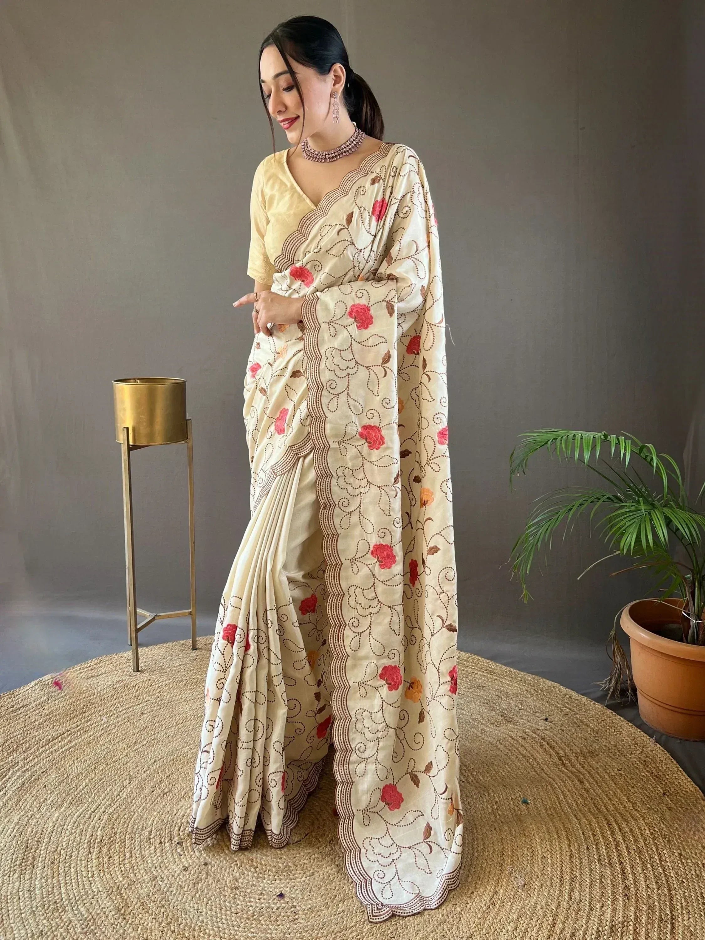 Cream saree with red floral embroidery and scalloped border, paired with yellow blouse for ethnic wear