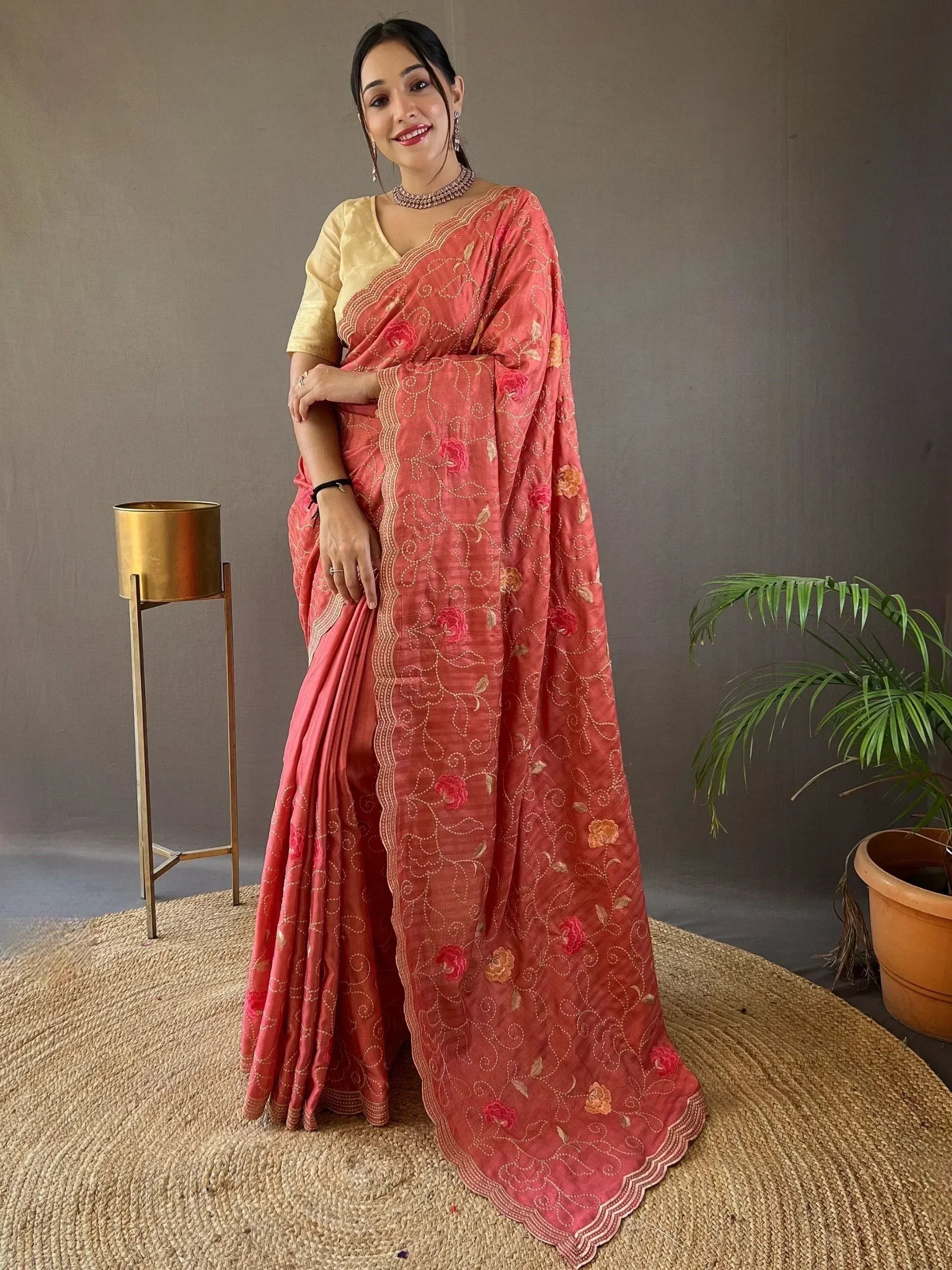 Woman in coral pink embroidered saree with floral motifs and gold blouse, Indian ethnic wear