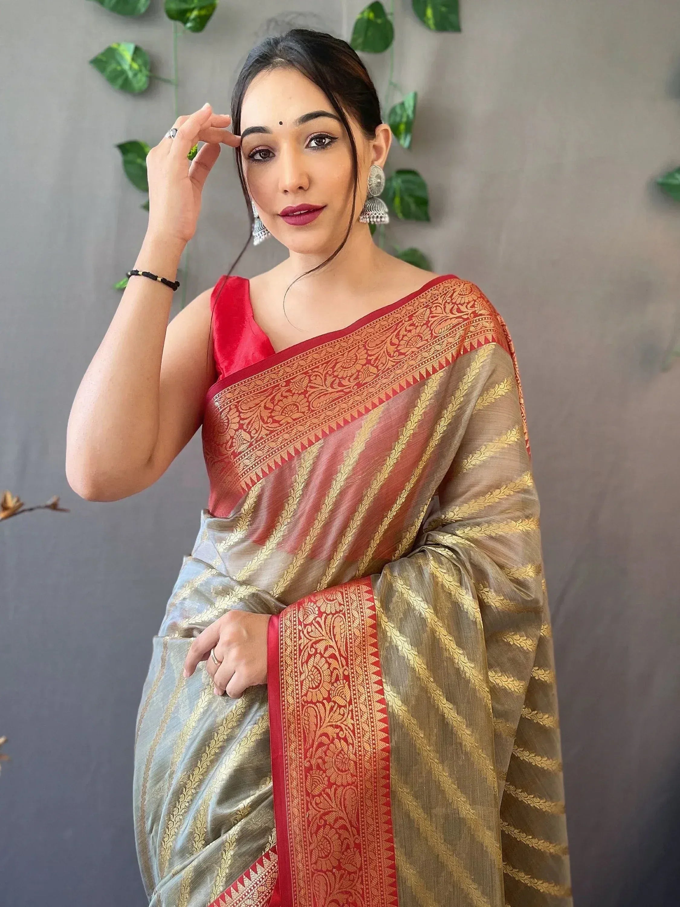 Woman in elegant red and gold saree with intricate border, styled with traditional earrings for ethnic wear