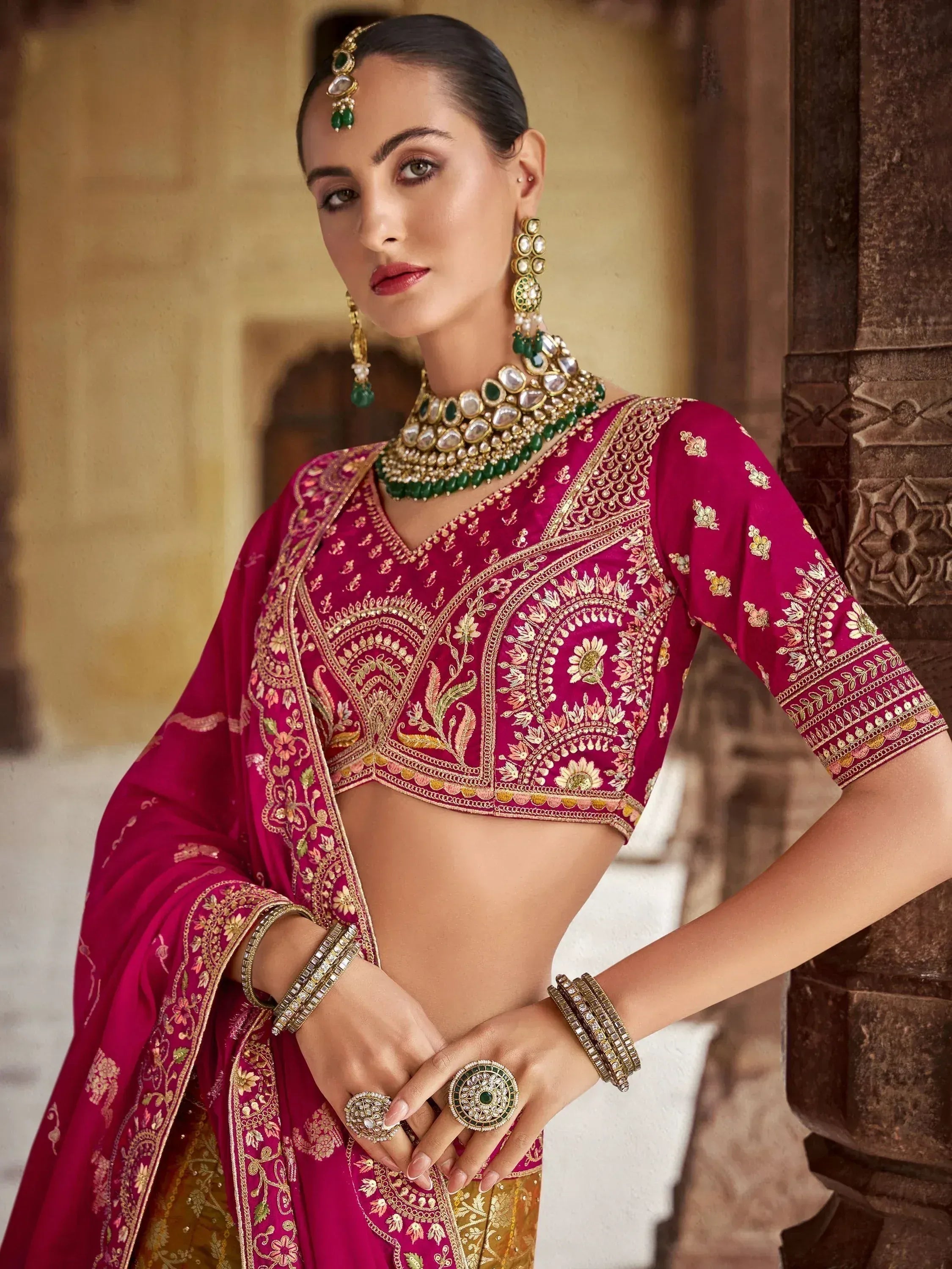 Elegant magenta lehenga choli with gold embroidery, paired with traditional Indian jewelry for festive occasions.