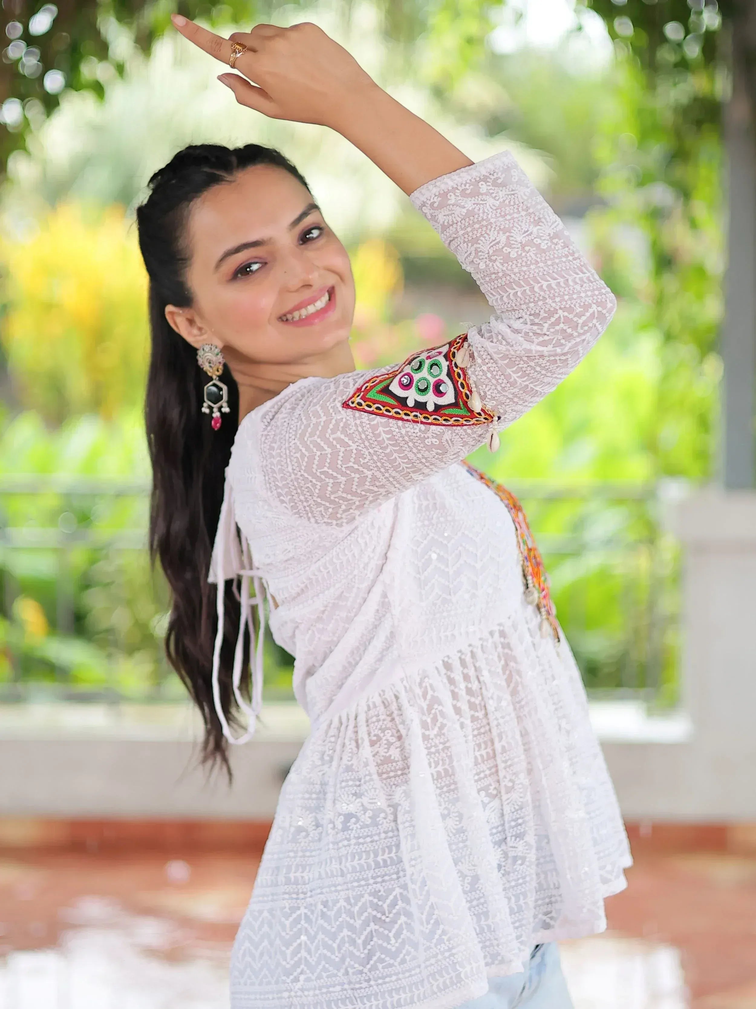 Woman in white lace ethnic top with colorful mirror work, smiling outdoors