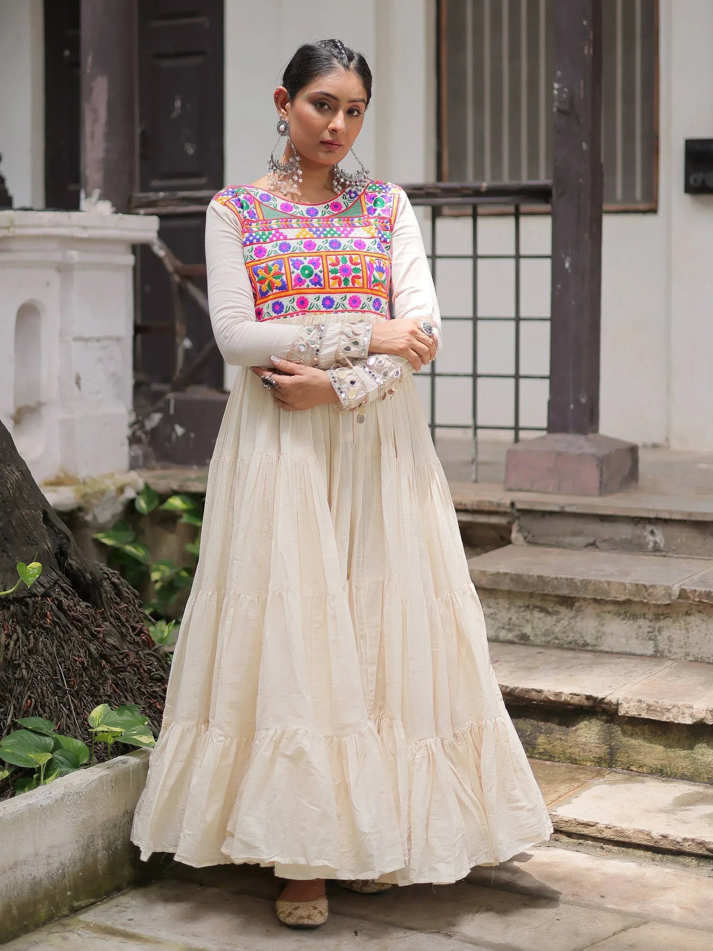 Woman in cream ethnic gown with colorful floral embroidery, traditional Indian wear