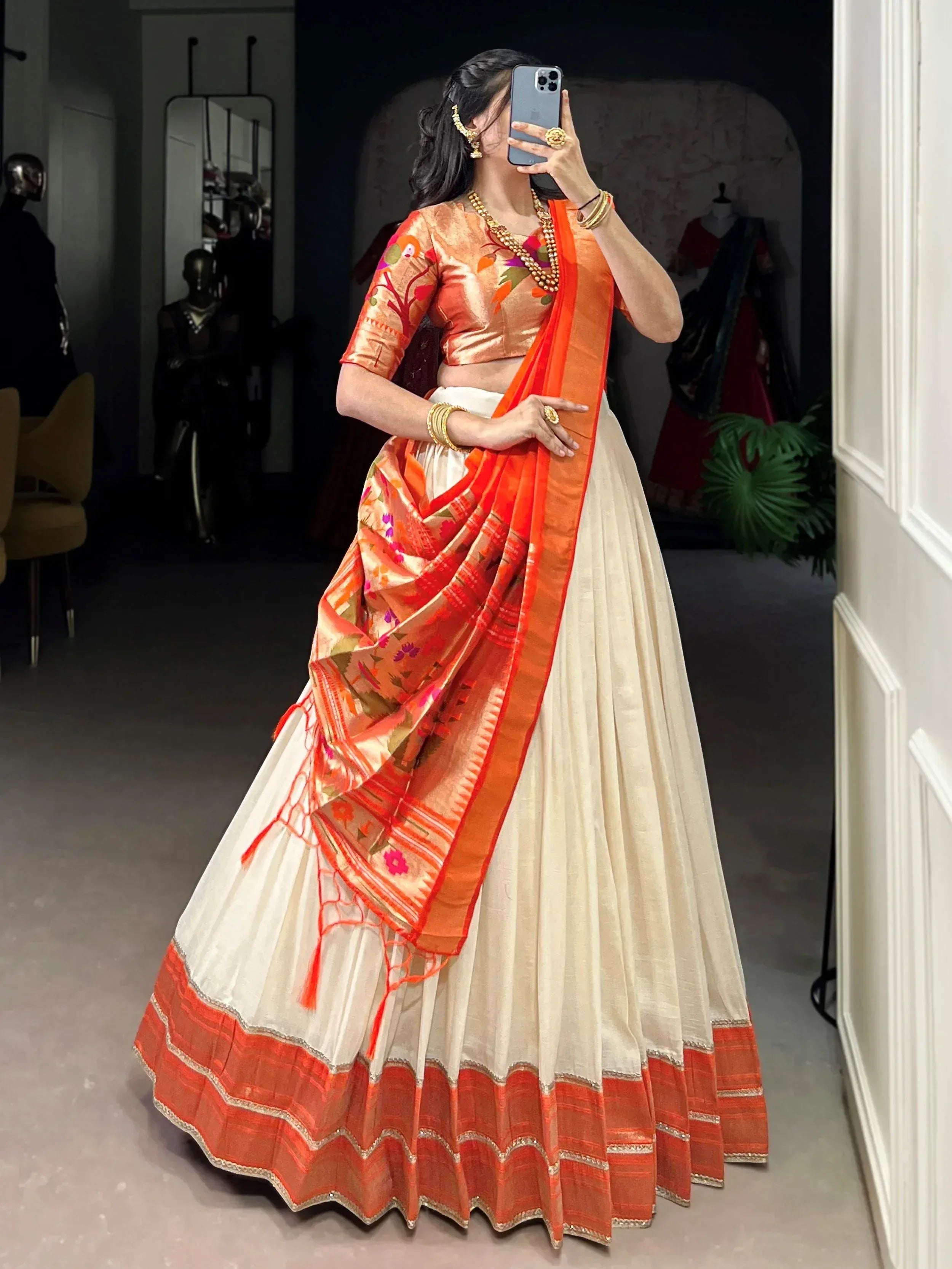 Woman in orange and cream lehenga choli with floral blouse, perfect for Indian ethnic wear occasions.