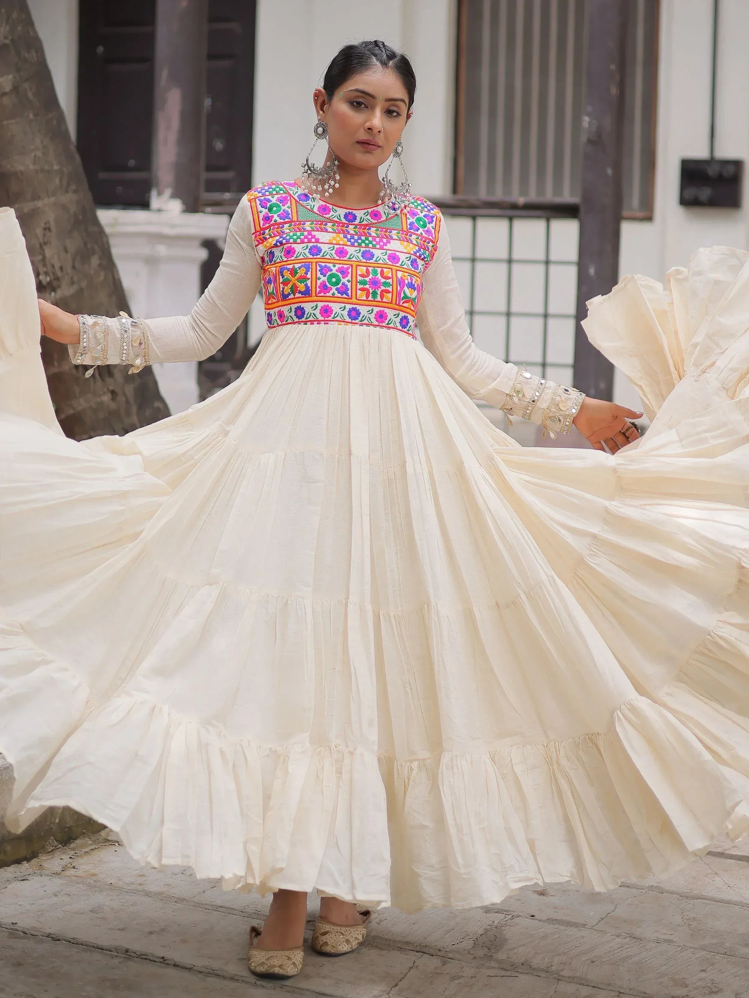 Woman in white ethnic gown with colorful floral embroidery, perfect for Indian festive occasions
