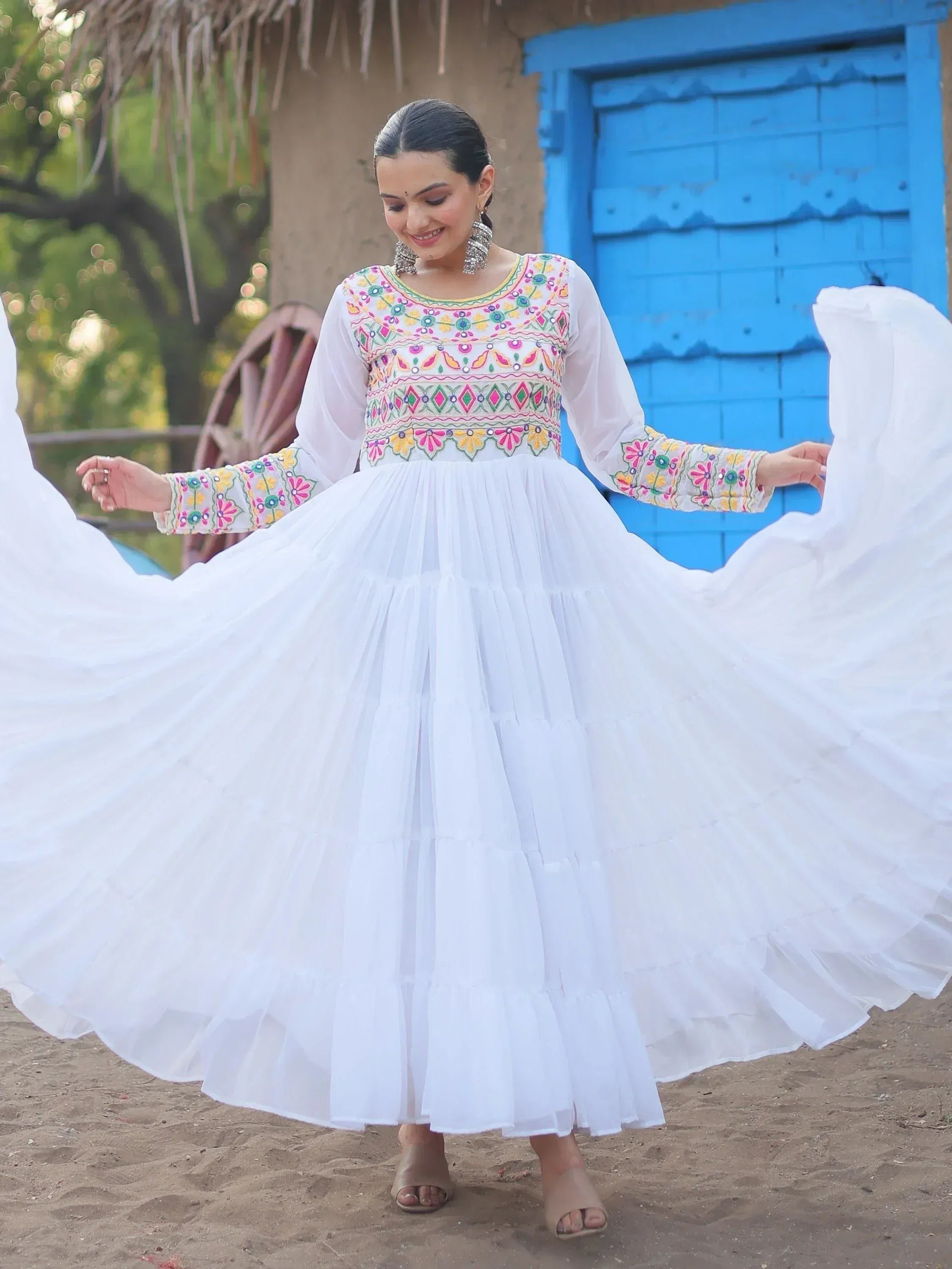 White embroidered ethnic gown with flared skirt, colorful mirror work, perfect for festive occasions