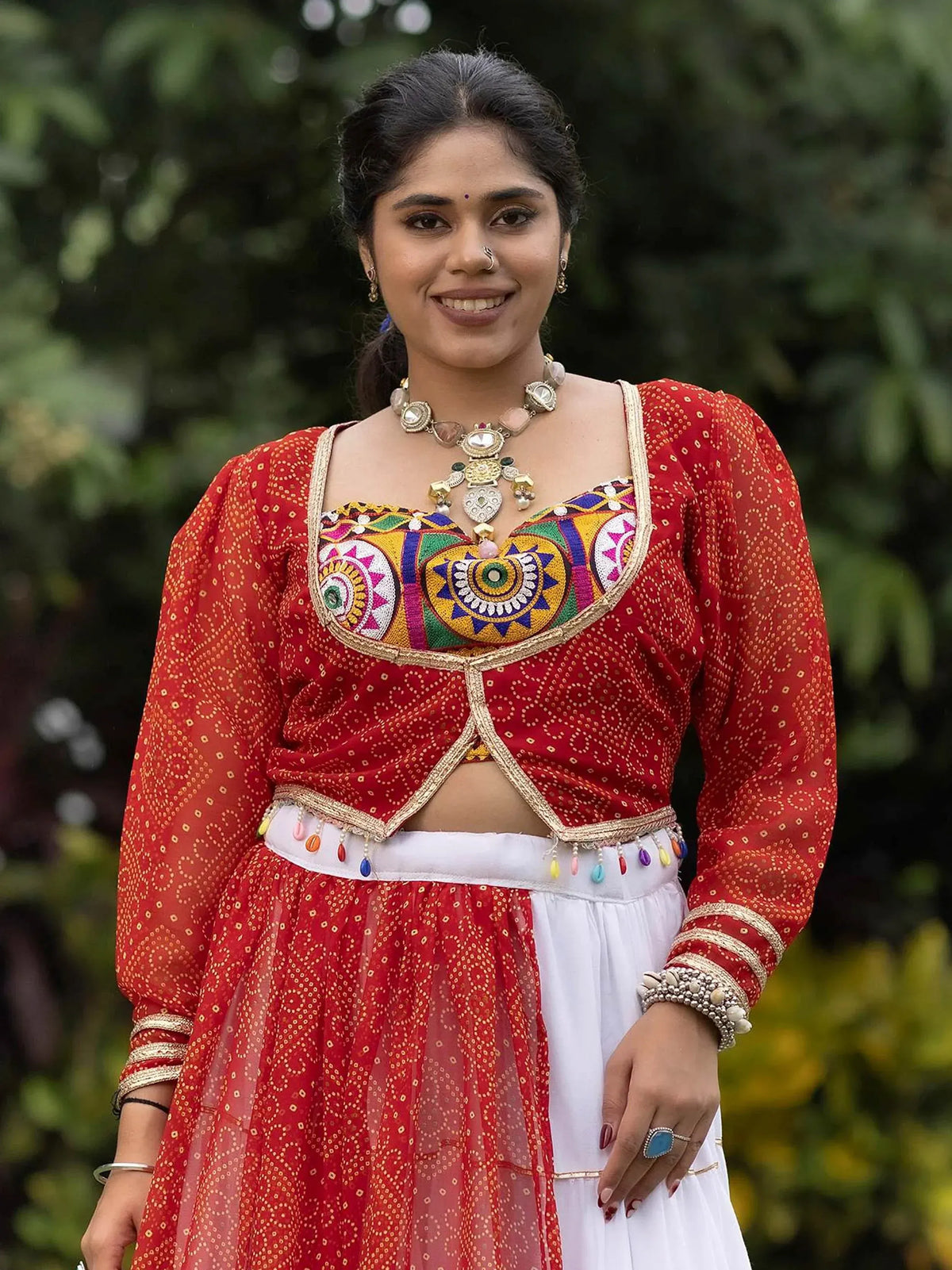 Woman in red and white ethnic lehenga choli with colorful embroidery and traditional jewelry