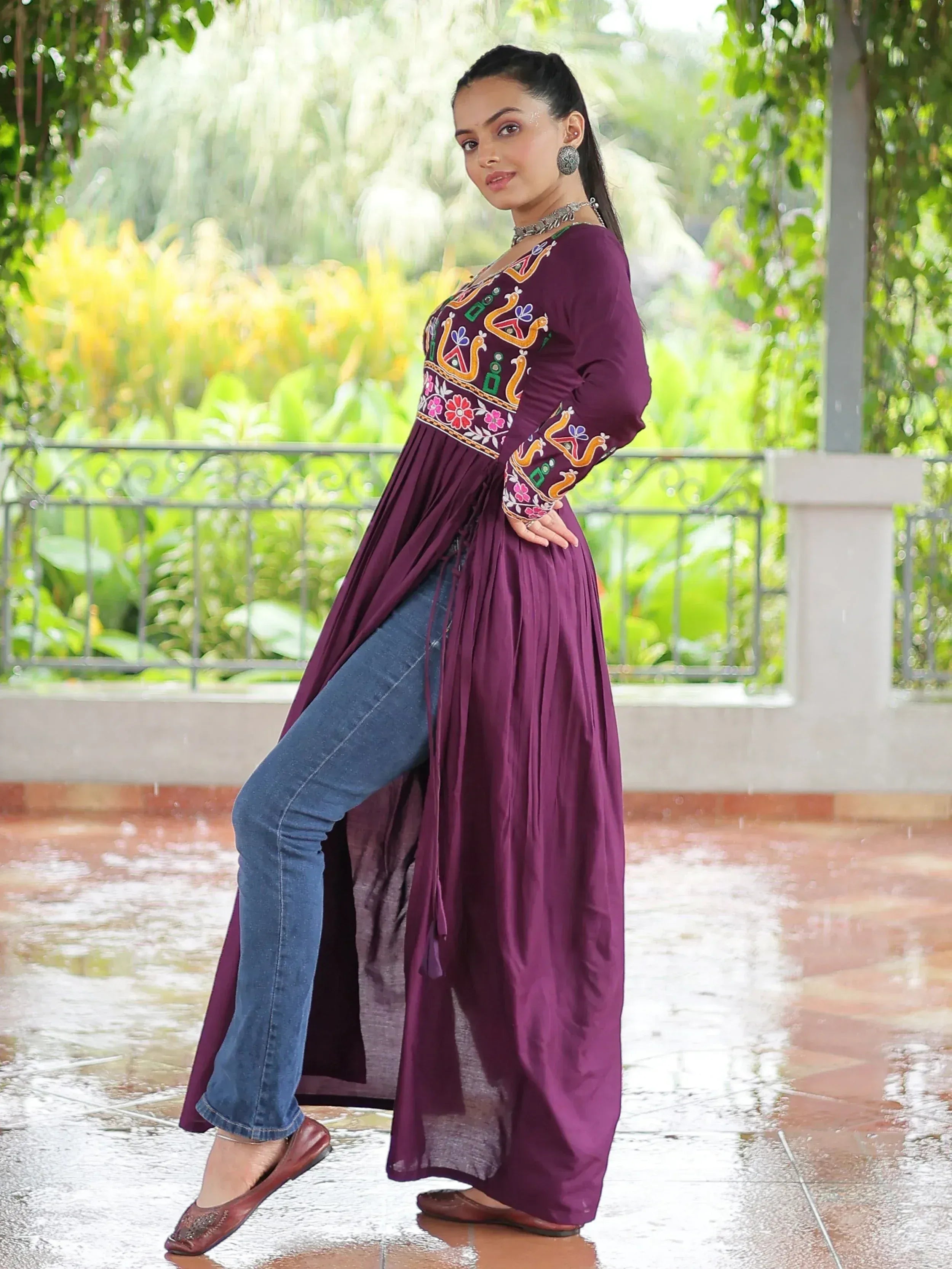 Purple embroidered ethnic gown with floral patterns, paired with jeans, perfect for festive occasions.