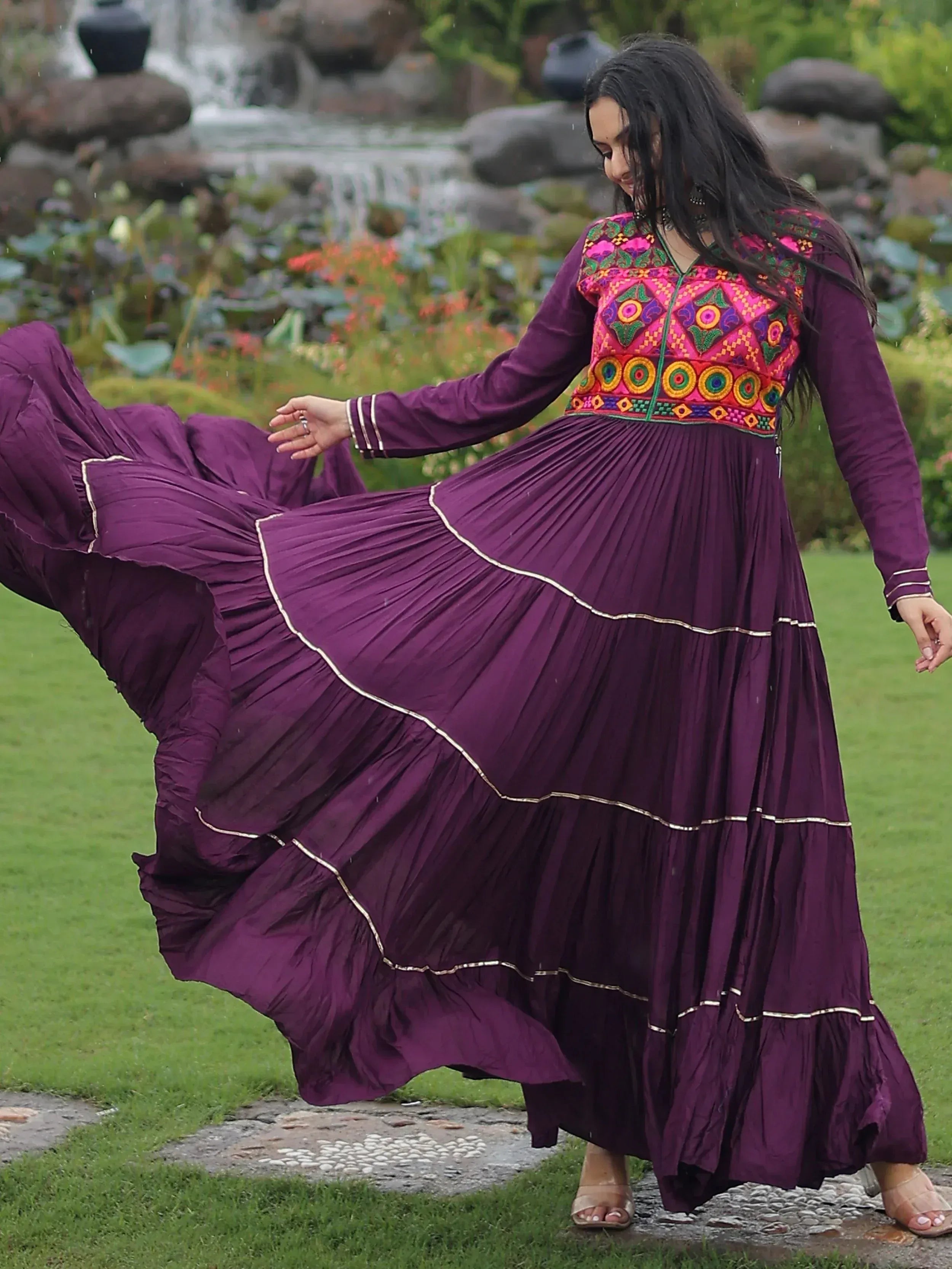 Woman twirling in purple ethnic gown with vibrant embroidery, perfect for Indian festive occasions