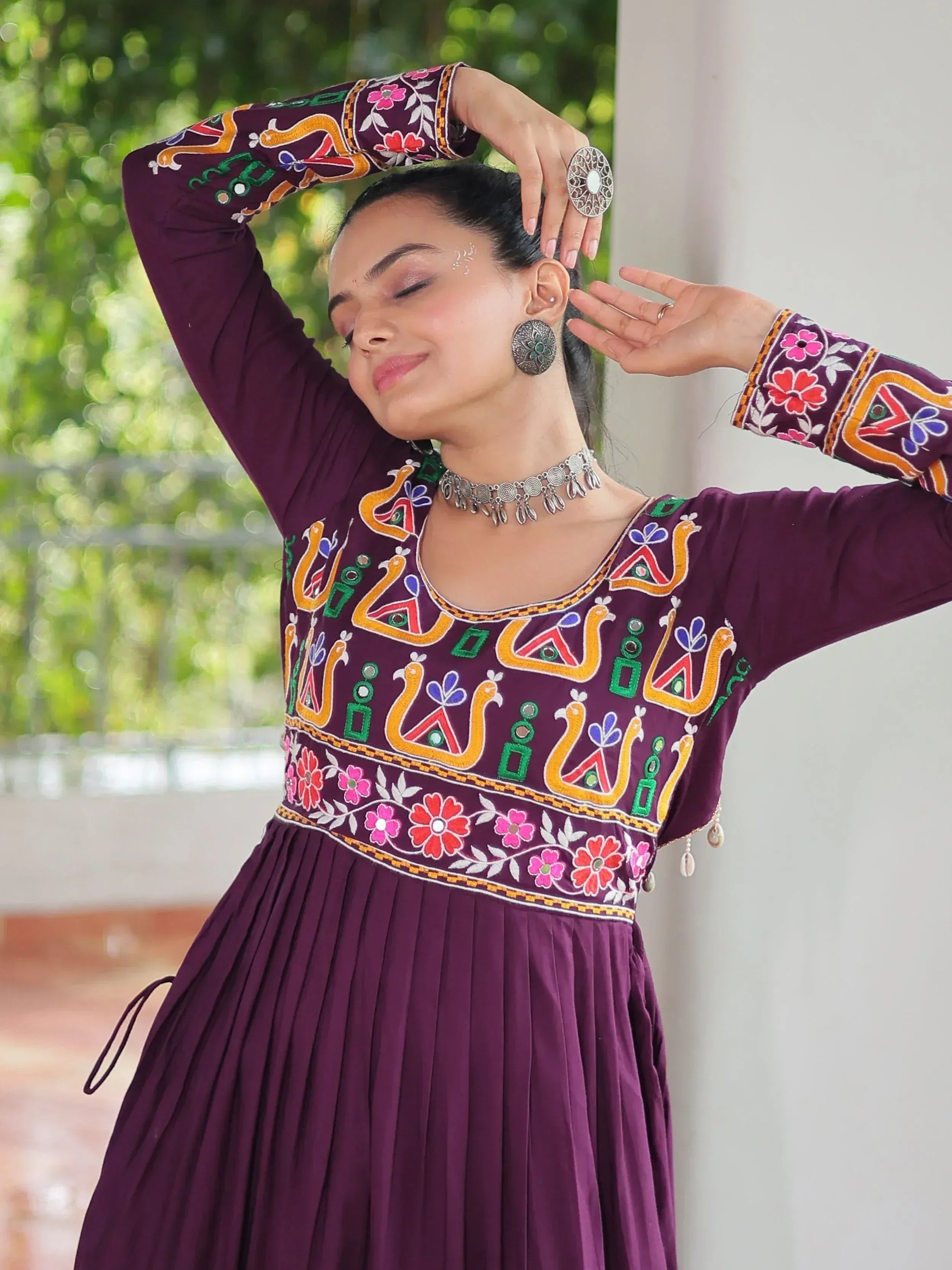 Woman in purple embroidered ethnic gown with floral and peacock motifs, styled with silver jewelry