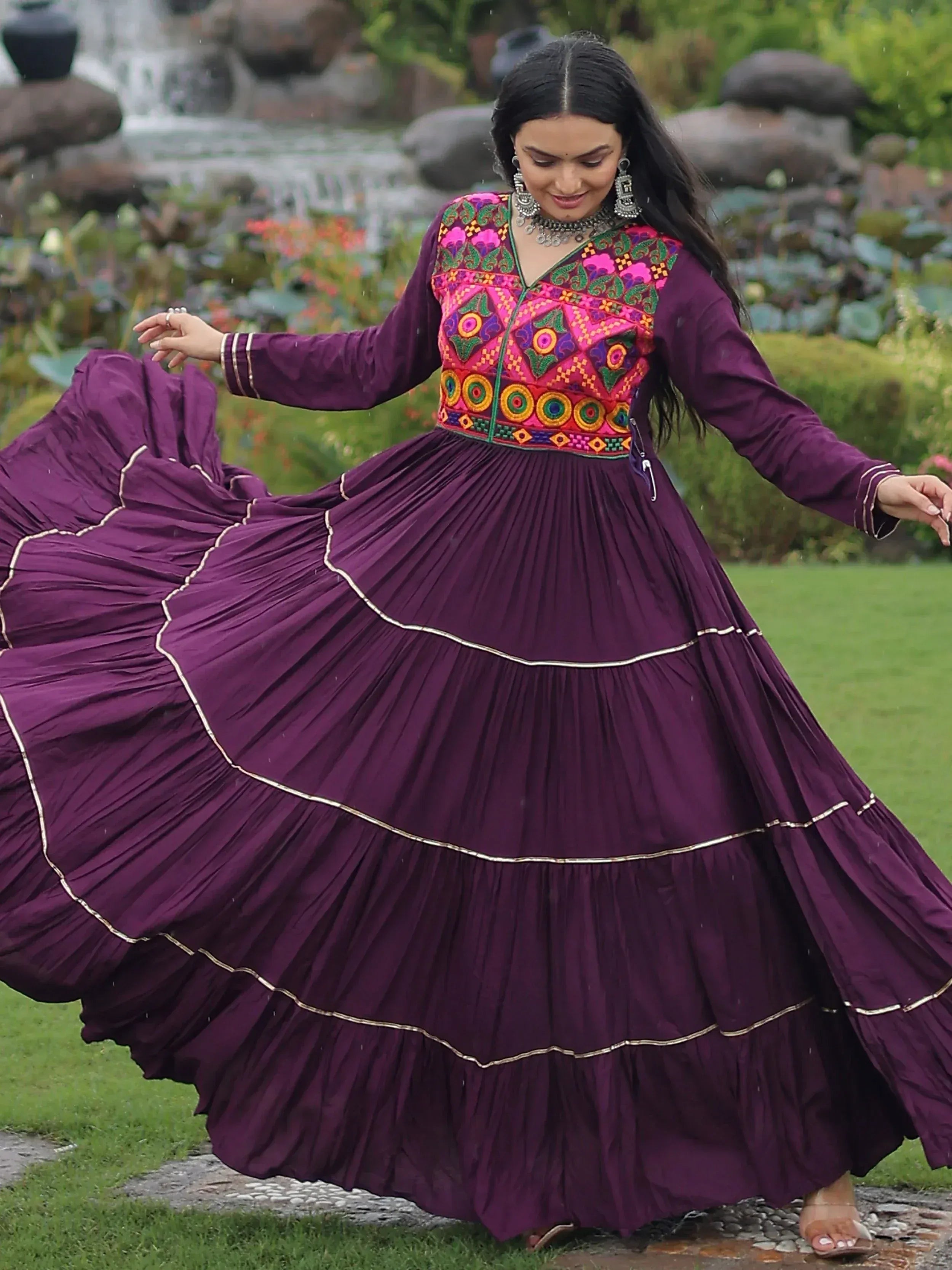 Woman twirling in purple ethnic gown with colorful embroidery, perfect for festive occasions