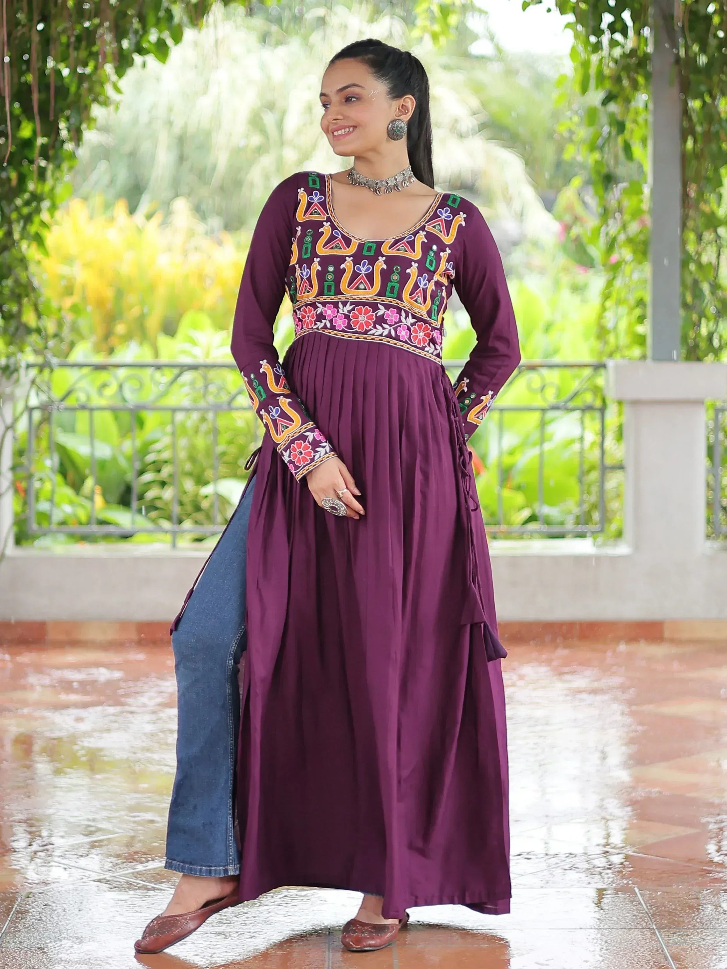 Purple embroidered ethnic kurti with floral and peacock motifs, paired with jeans, for a modern fusion look.