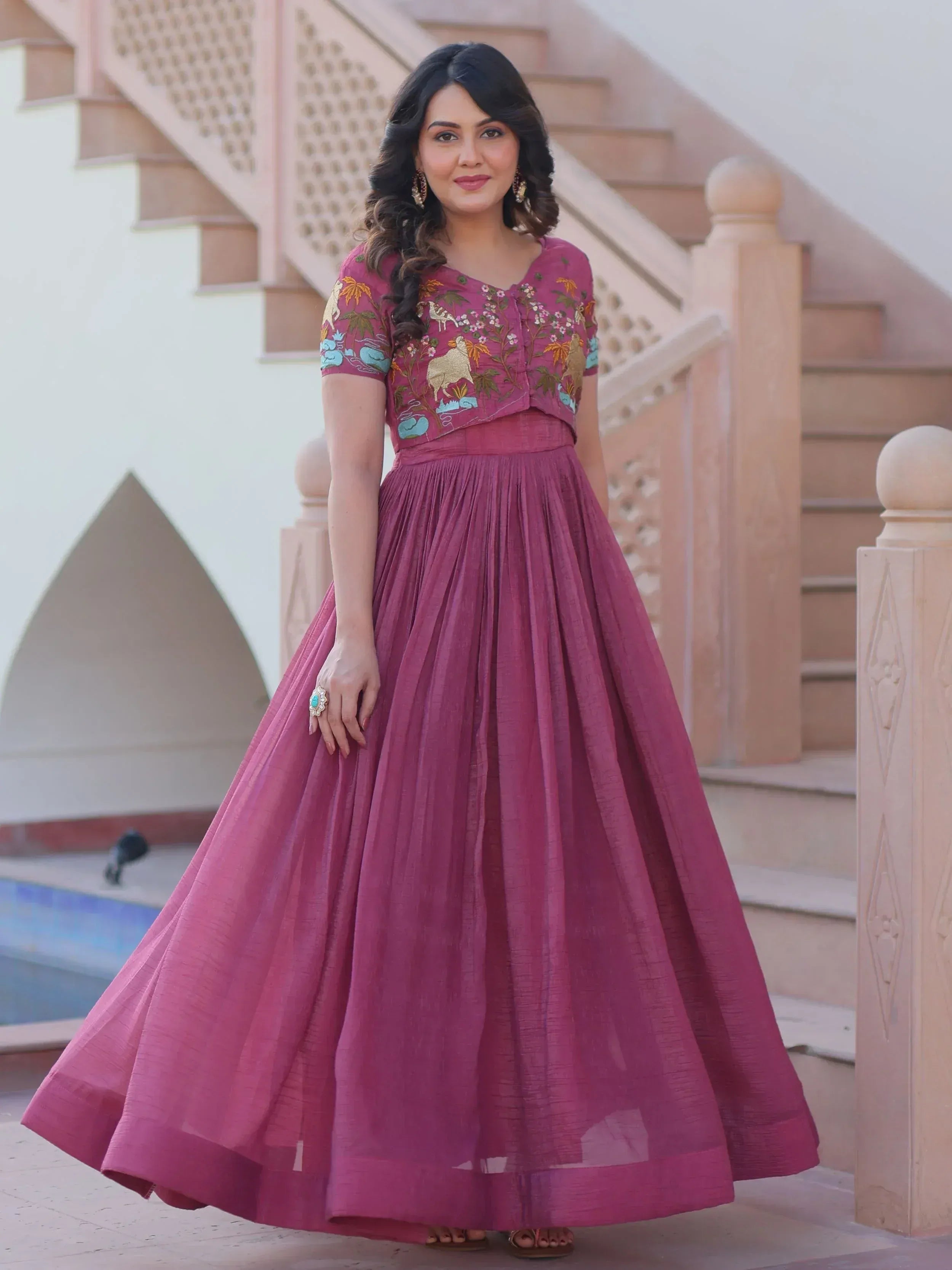 Woman in maroon ethnic gown with floral and animal embroidery, perfect for Indian occasions