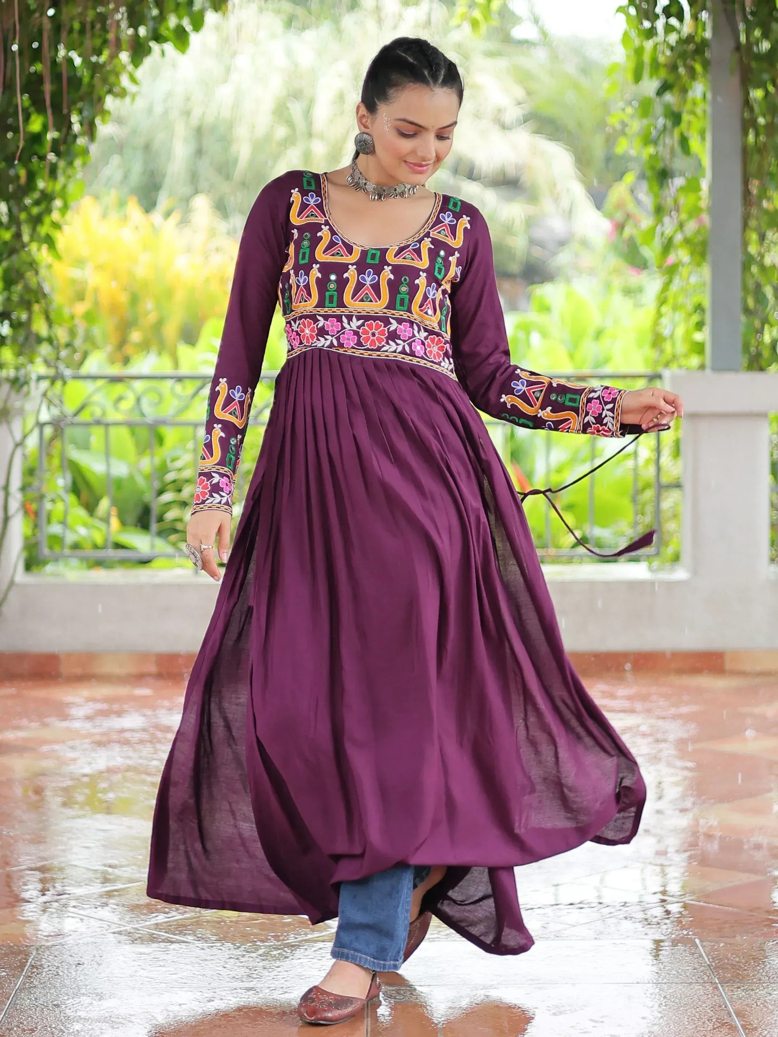 Purple embroidered ethnic gown with floral patterns, paired with jeans, perfect for festive occasions.