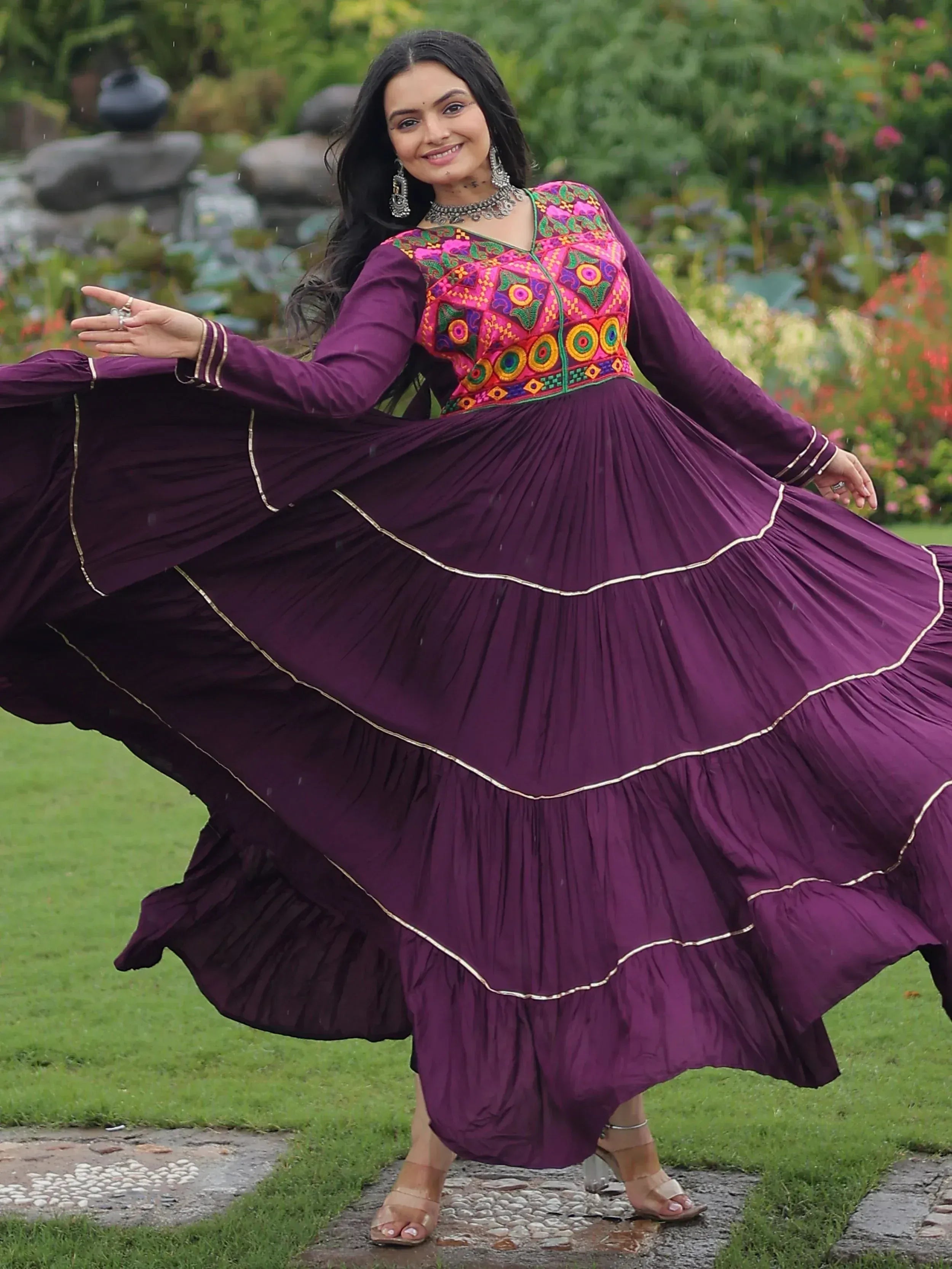 Woman twirling in purple ethnic gown with colorful embroidery, perfect for Indian festive occasions.