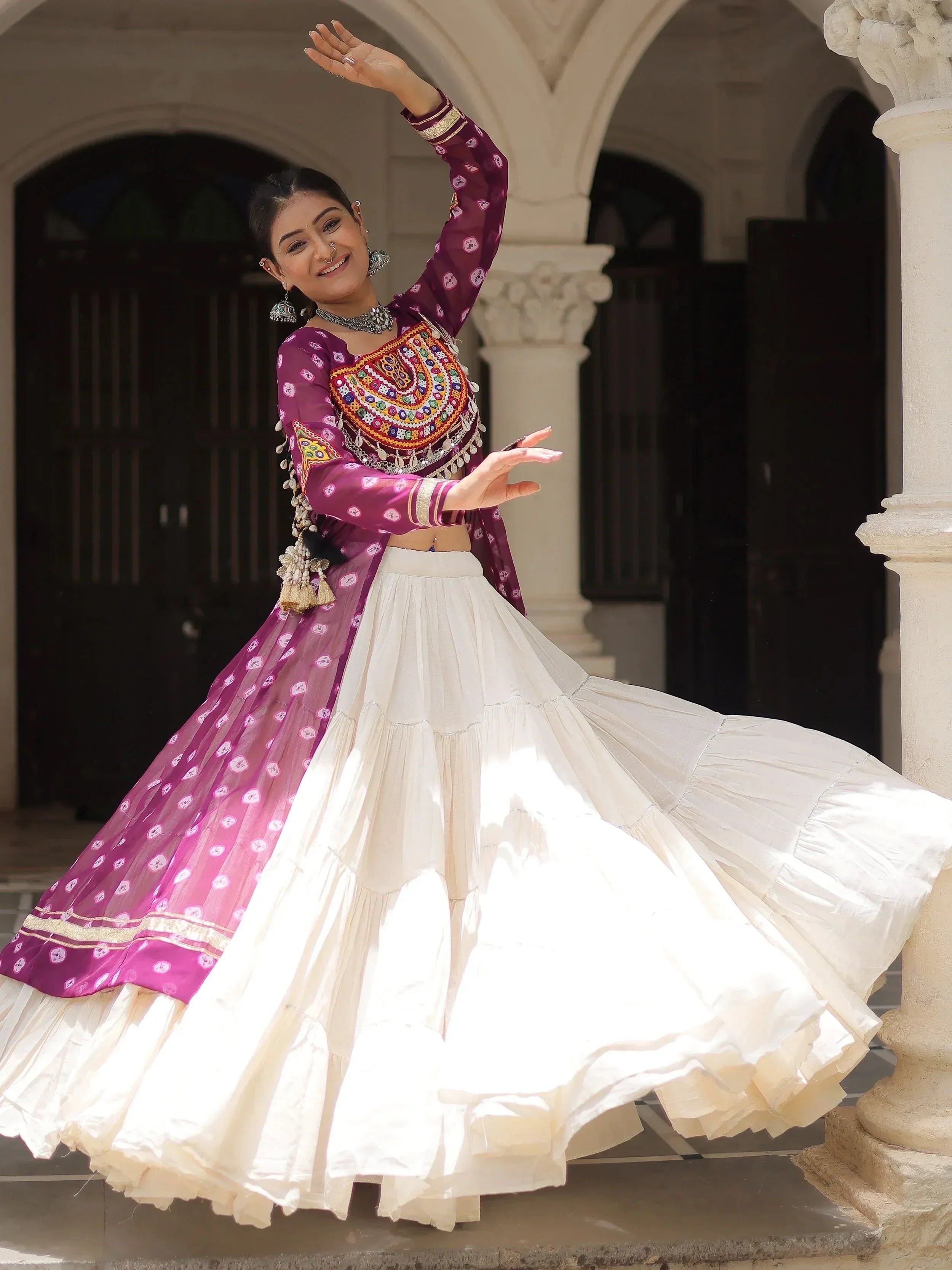 Woman in purple embroidered choli and white lehenga dancing at courtyard