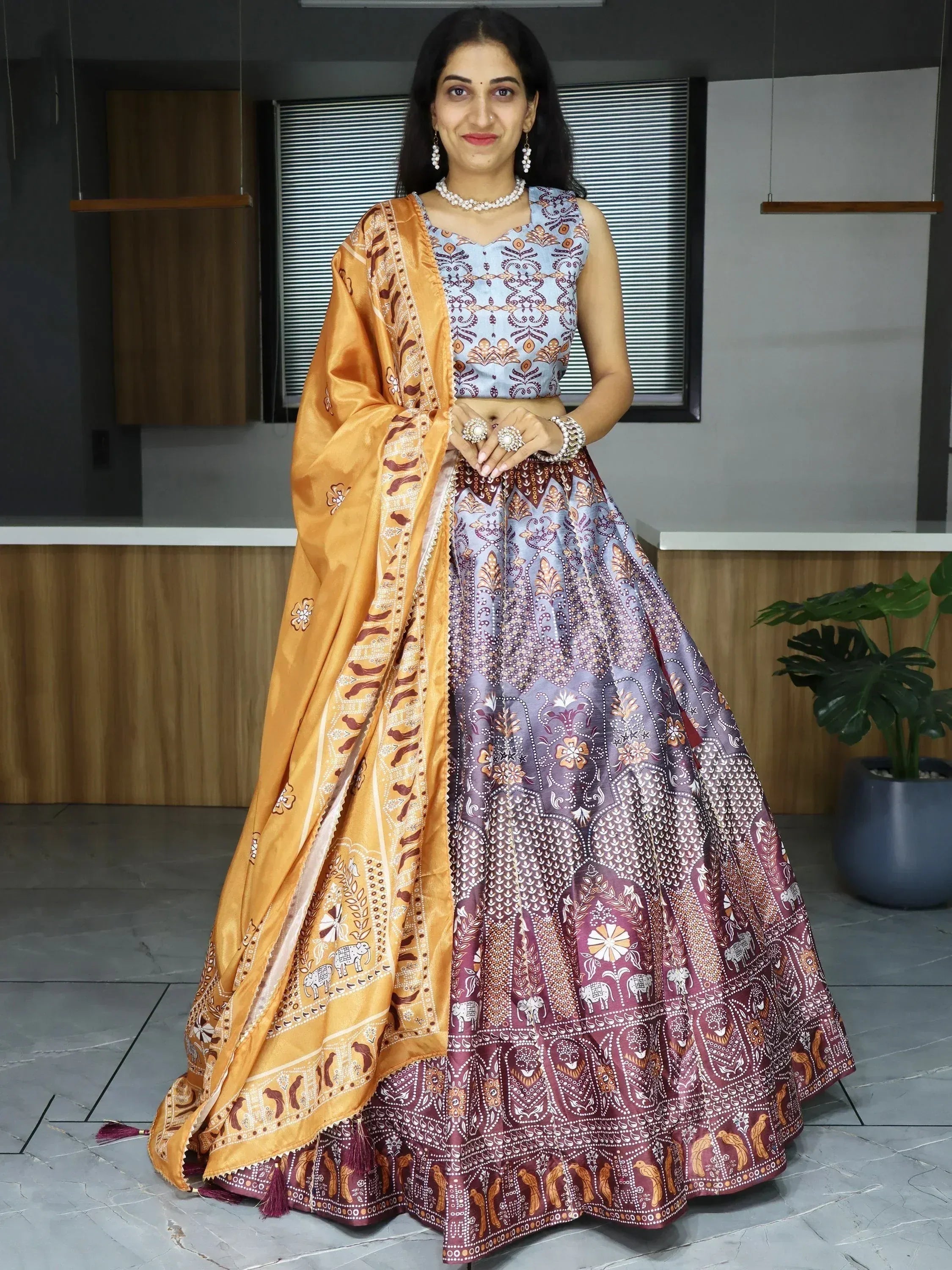 Woman in designer lehenga choli with elephant print, orange dupatta, and ethnic jewelry for Indian occasions