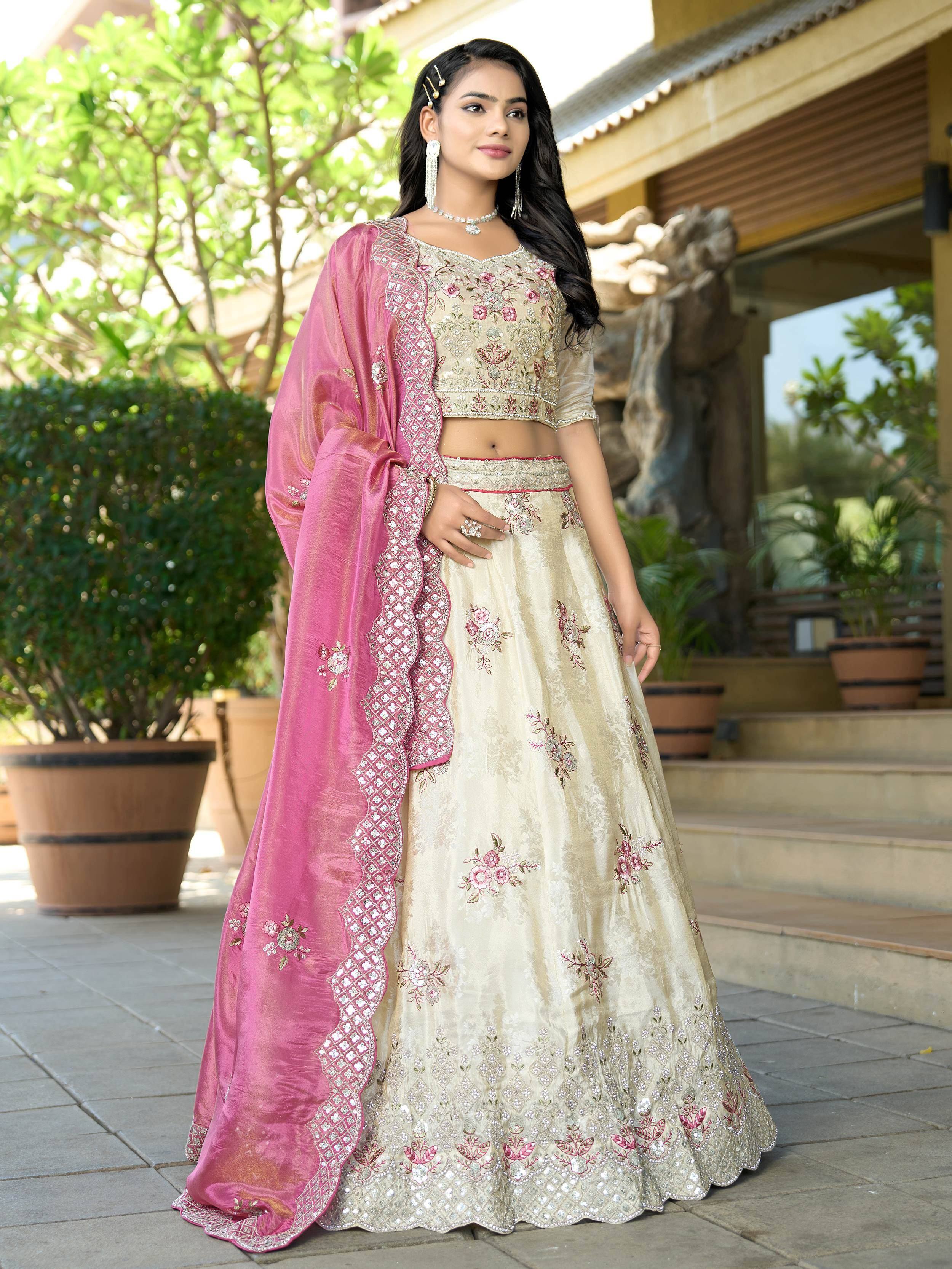 Elegant cream and pink embroidered lehenga choli with floral motifs and matching dupatta, perfect for Indian ethnic occasions.