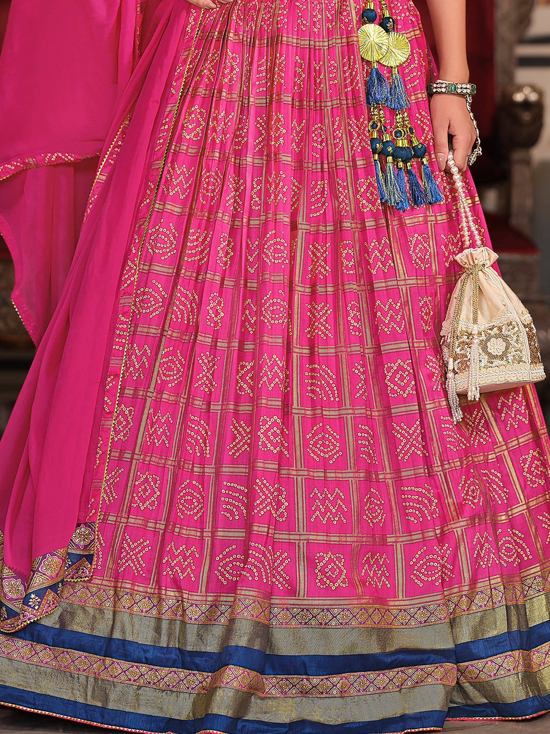Pink ethnic lehenga with gold embroidery, blue tassels, and matching potli bag for Indian weddings