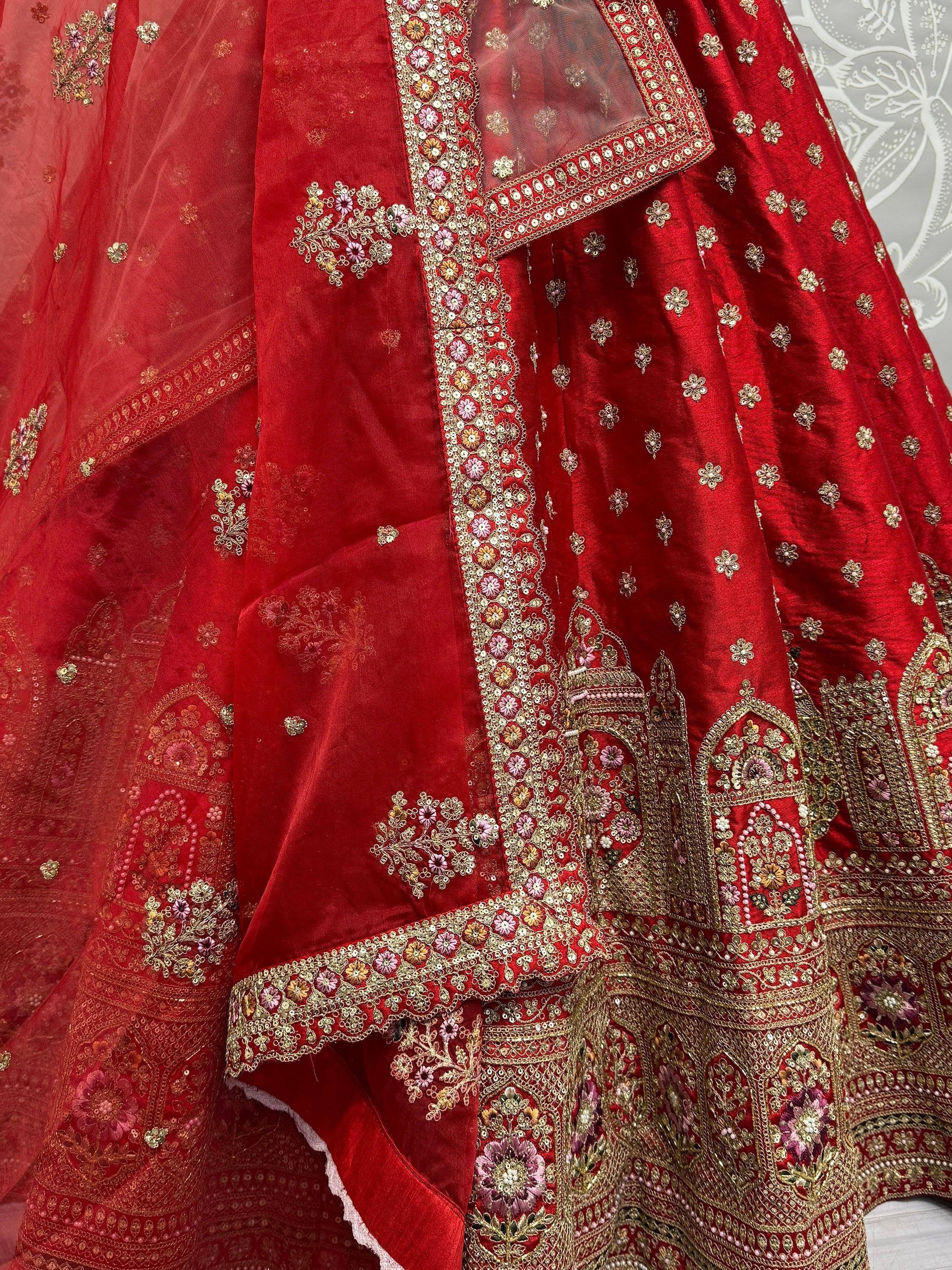 Red velvet lehenga choli with intricate floral embroidery and gold detailing, perfect for Indian weddings.