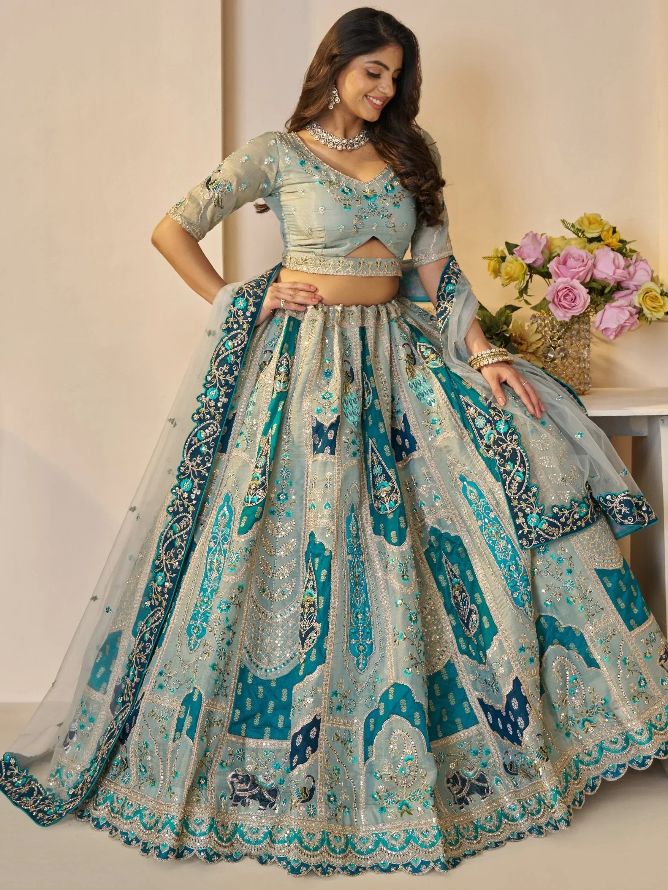 Teal and silver embroidered lehenga choli with floral and paisley designs, perfect for Indian weddings and festive occasions.