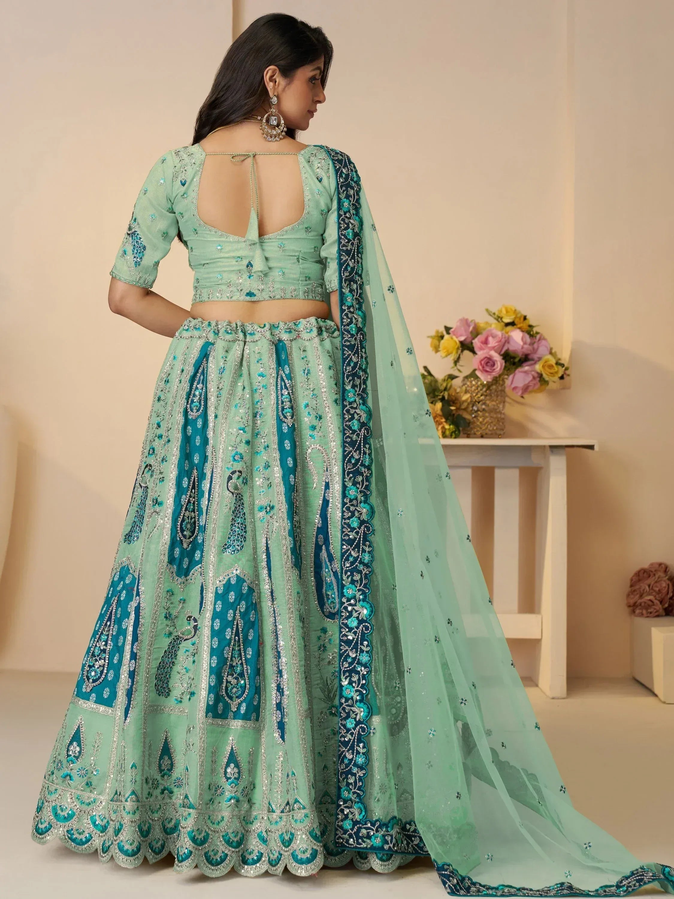 Mint green designer lehenga choli with peacock embroidery and sheer dupatta, perfect for Indian weddings and festive occasions.