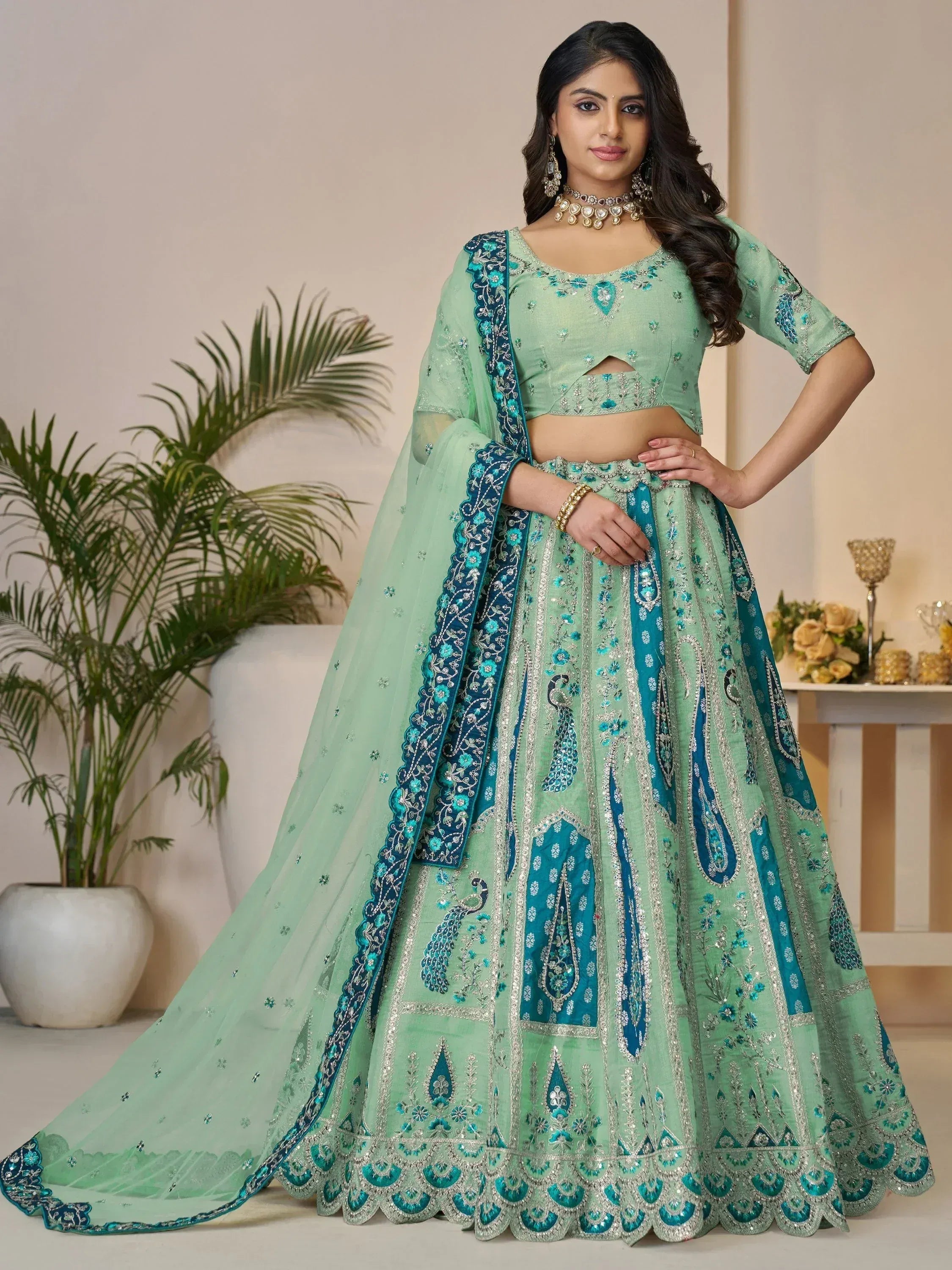 Mint green designer lehenga choli with peacock embroidery and blue border, perfect for Indian weddings and festive occasions.