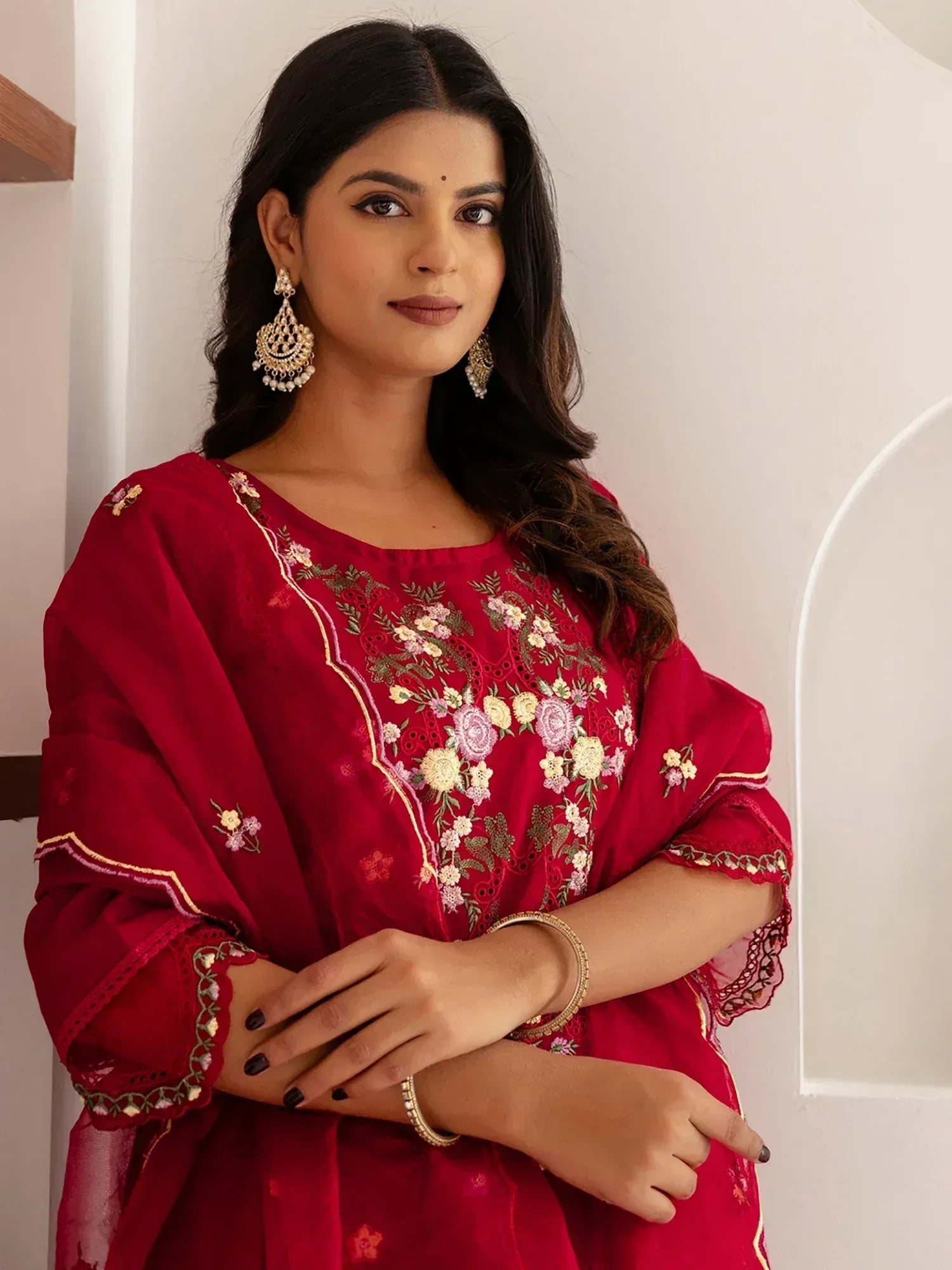 Woman in red embroidered ethnic kurti with floral design, gold jewelry, and stylish salwar kameez look