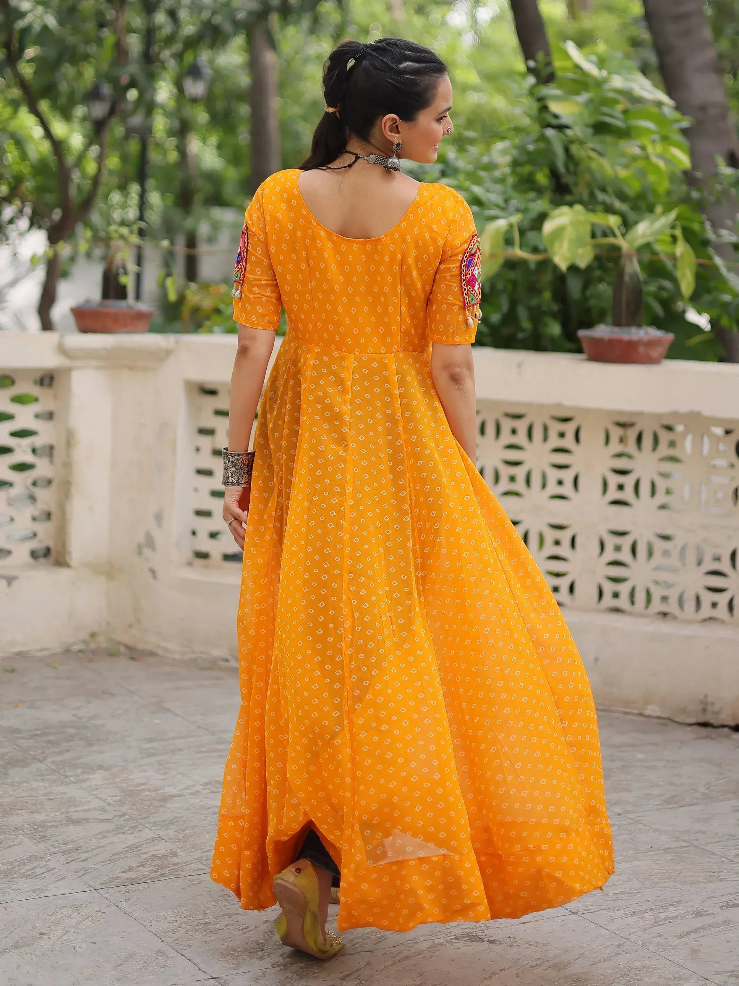 Woman in vibrant yellow ethnic gown with embroidered sleeves, perfect for Indian festive occasions