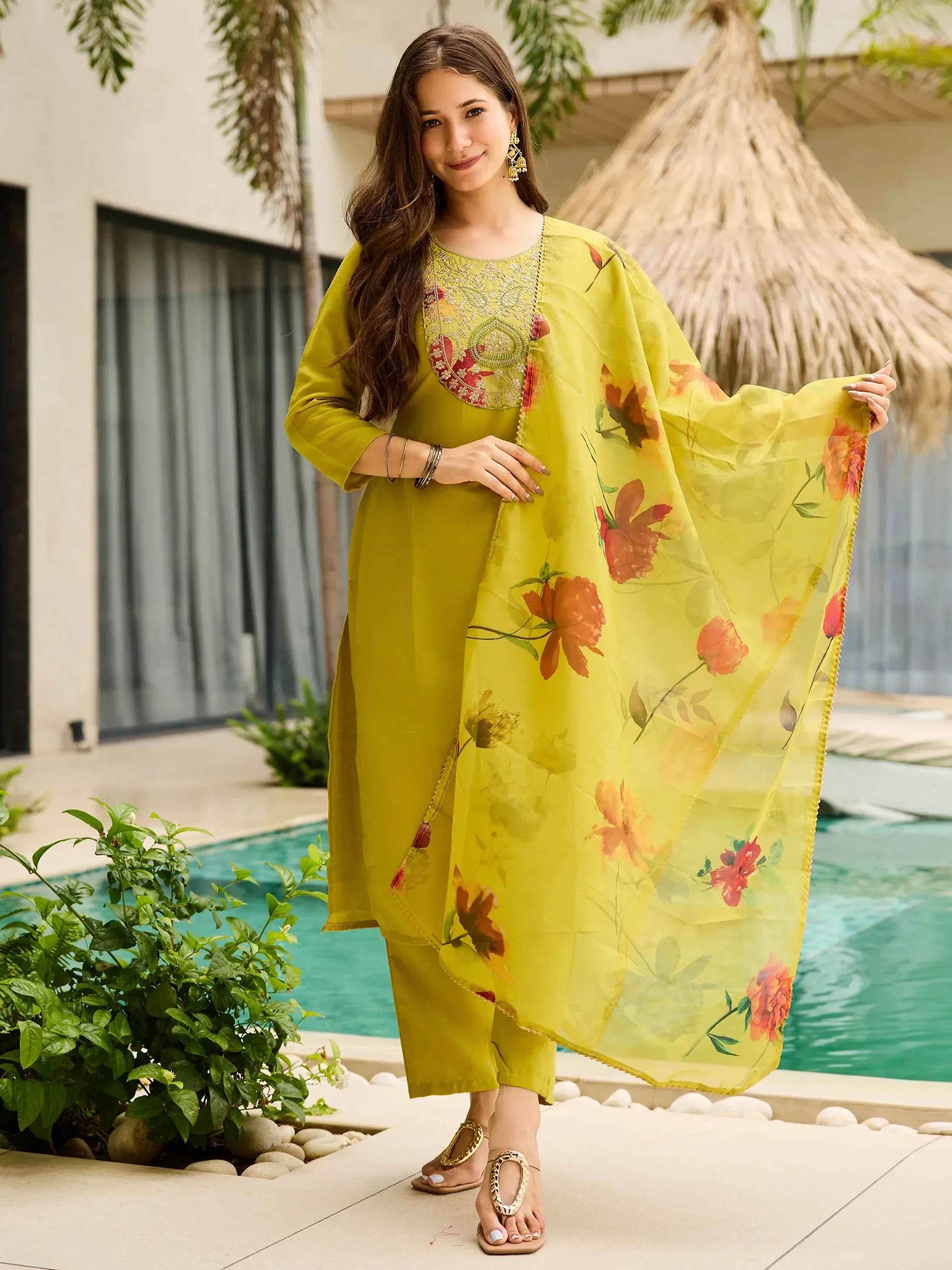 Woman in yellow floral salwar kameez with embroidered neckline, poolside setting