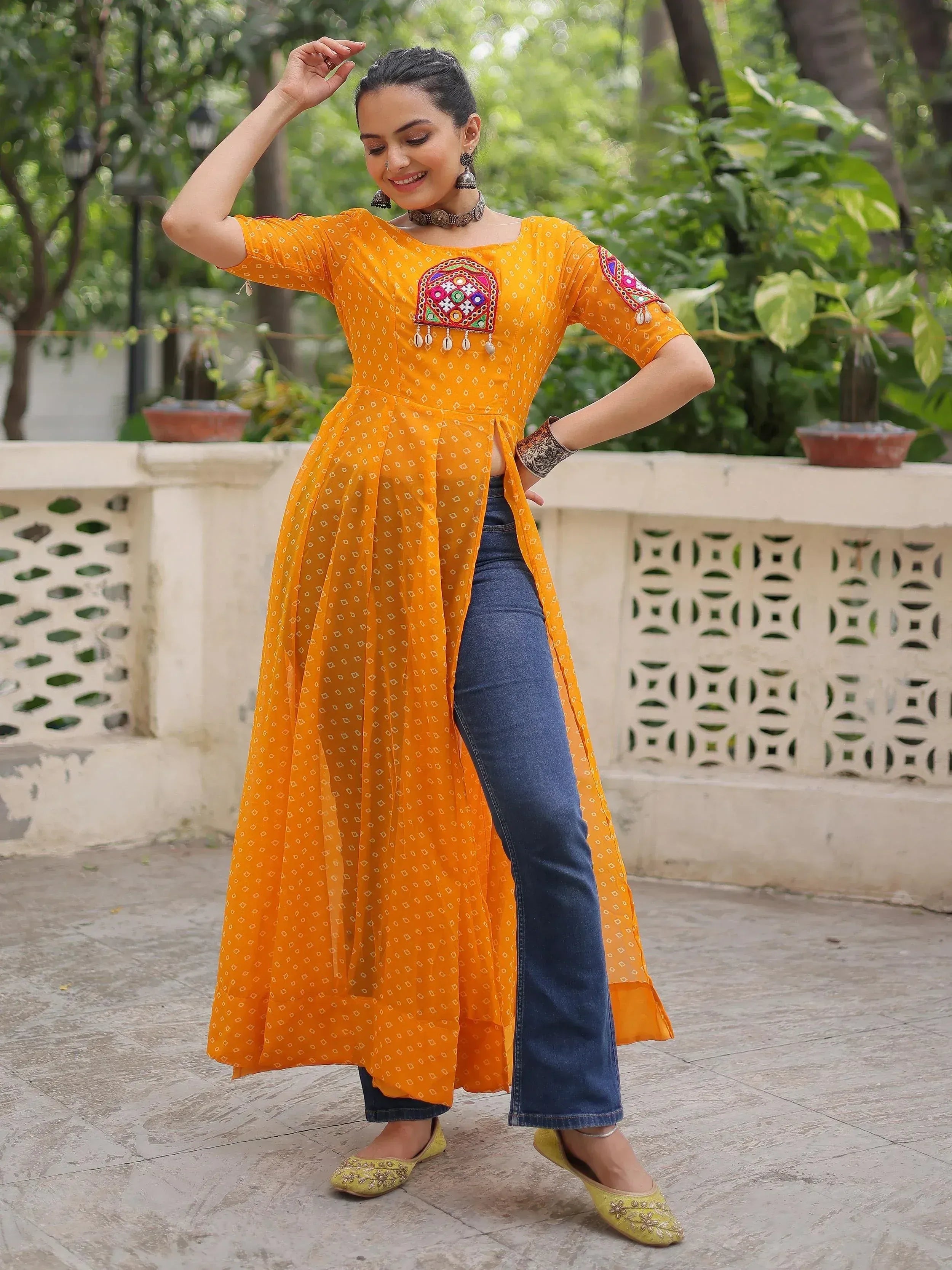 Woman in vibrant yellow ethnic kurta with mirror work, paired with jeans and juttis, styled for casual wear